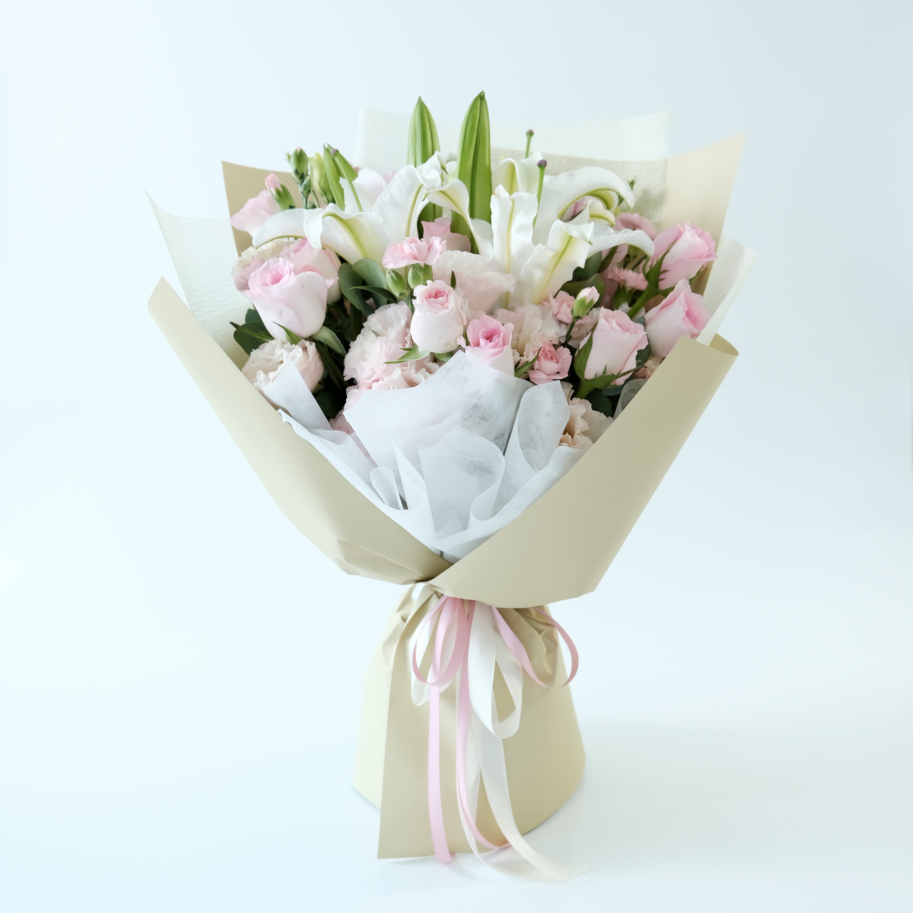 Bouquet of pink and white flowers wrapped in brown paper with a pink ribbon on a light blue background