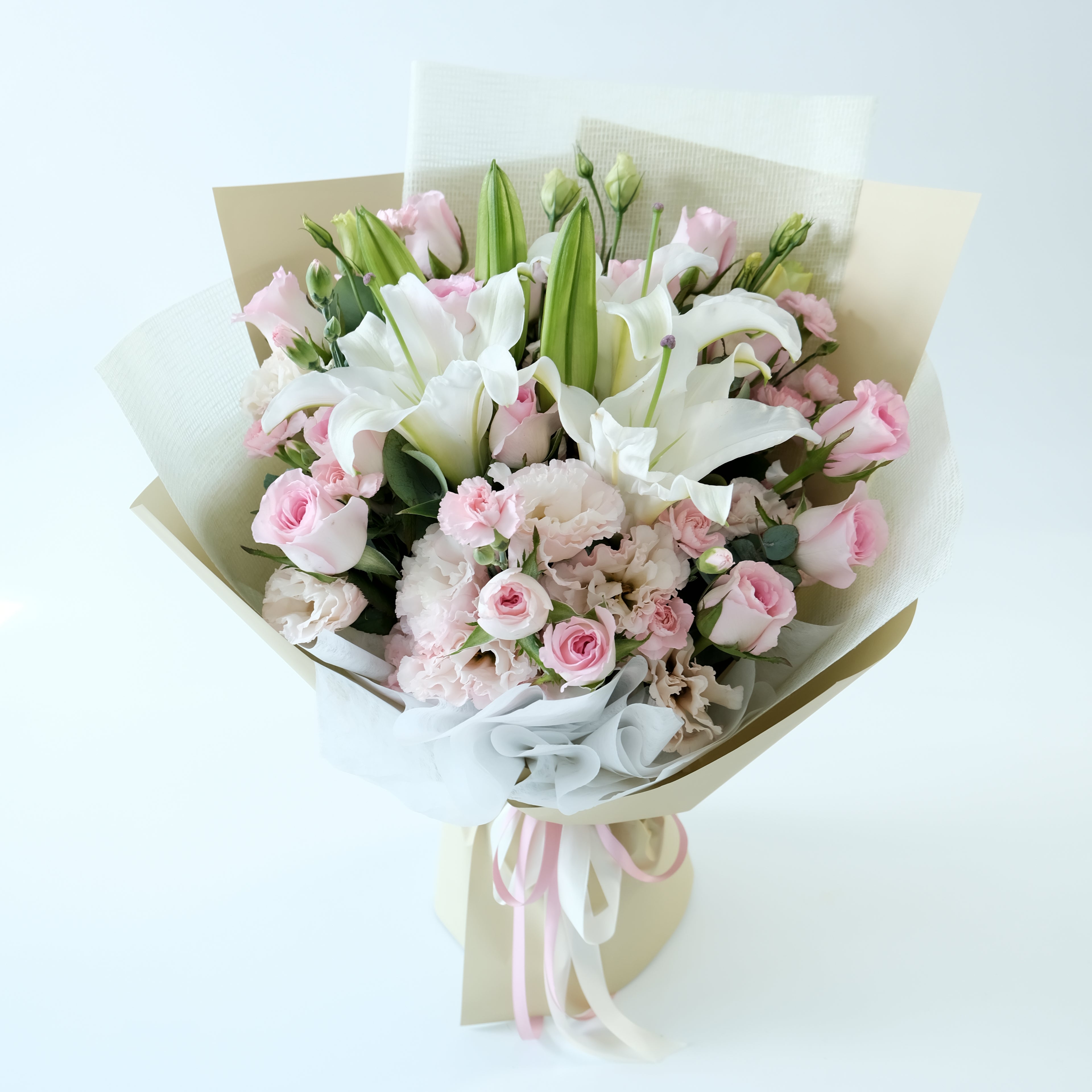 Bouquet of pink and white flowers wrapped in brown paper on a light background