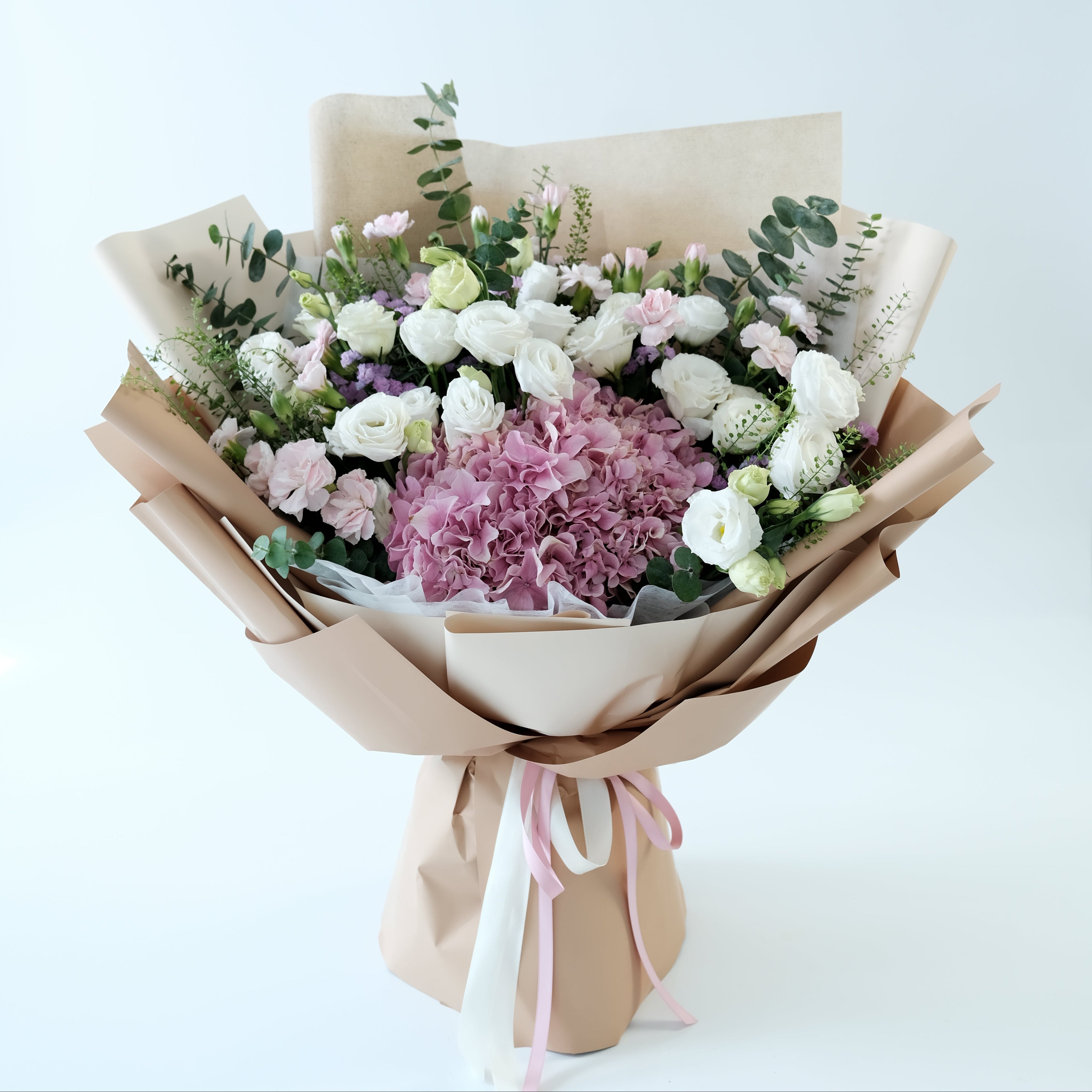 Bouquet of flowers wrapped in brown paper with a pink ribbon on a light blue background