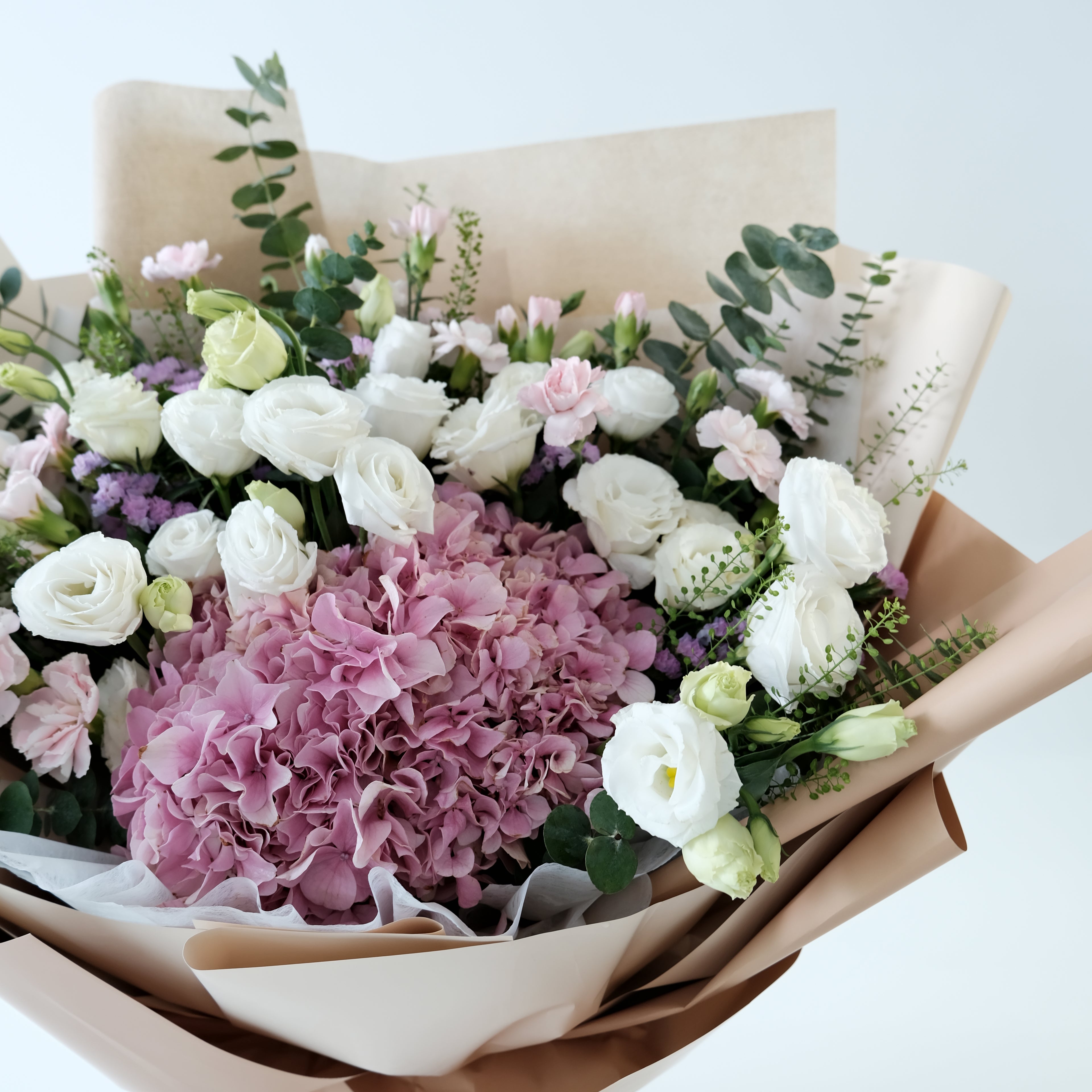 Bouquet of pink and white flowers with greenery on a light background