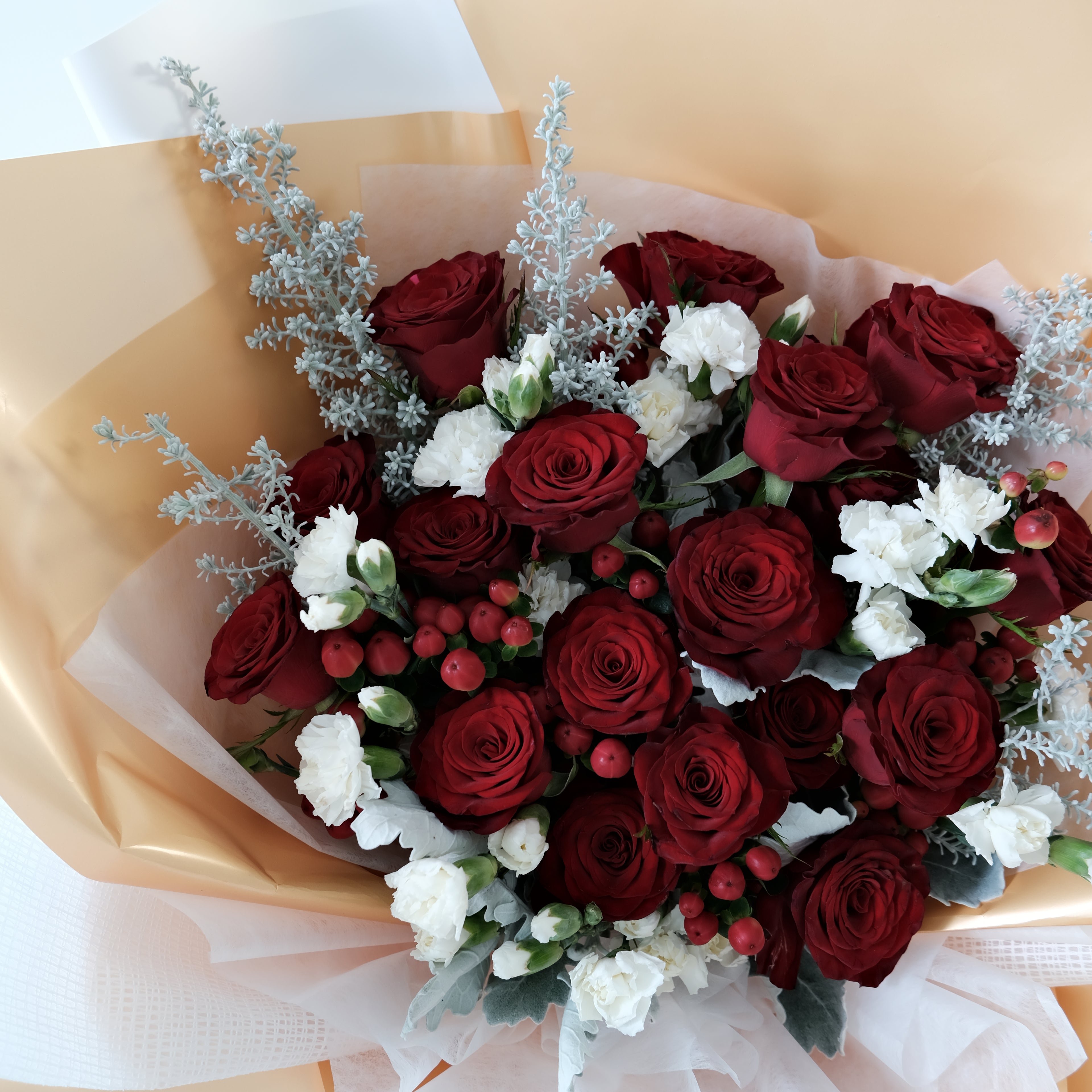 Bouquet of red roses and white flowers with gold wrapping paper