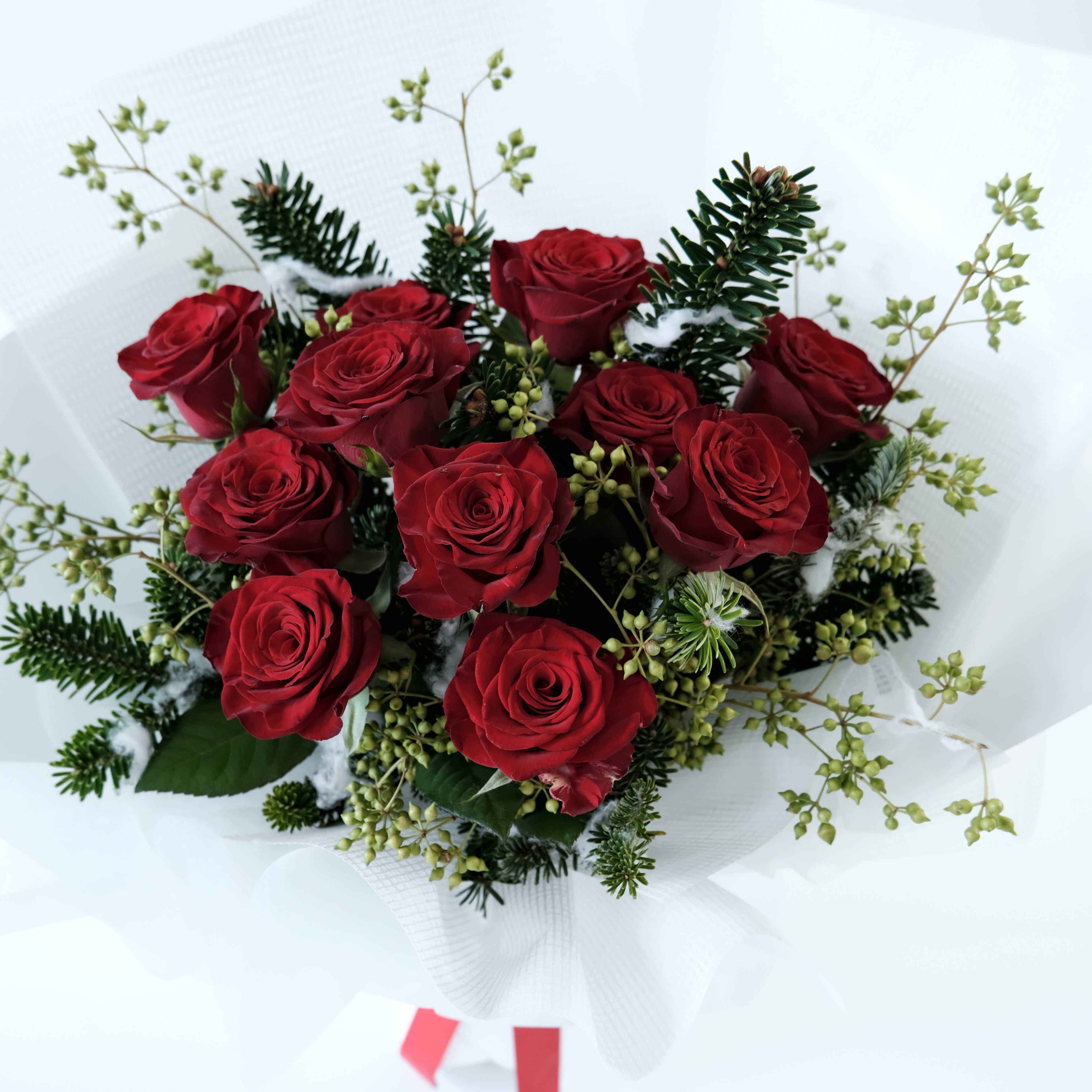 Bouquet of red roses with greenery on a white background