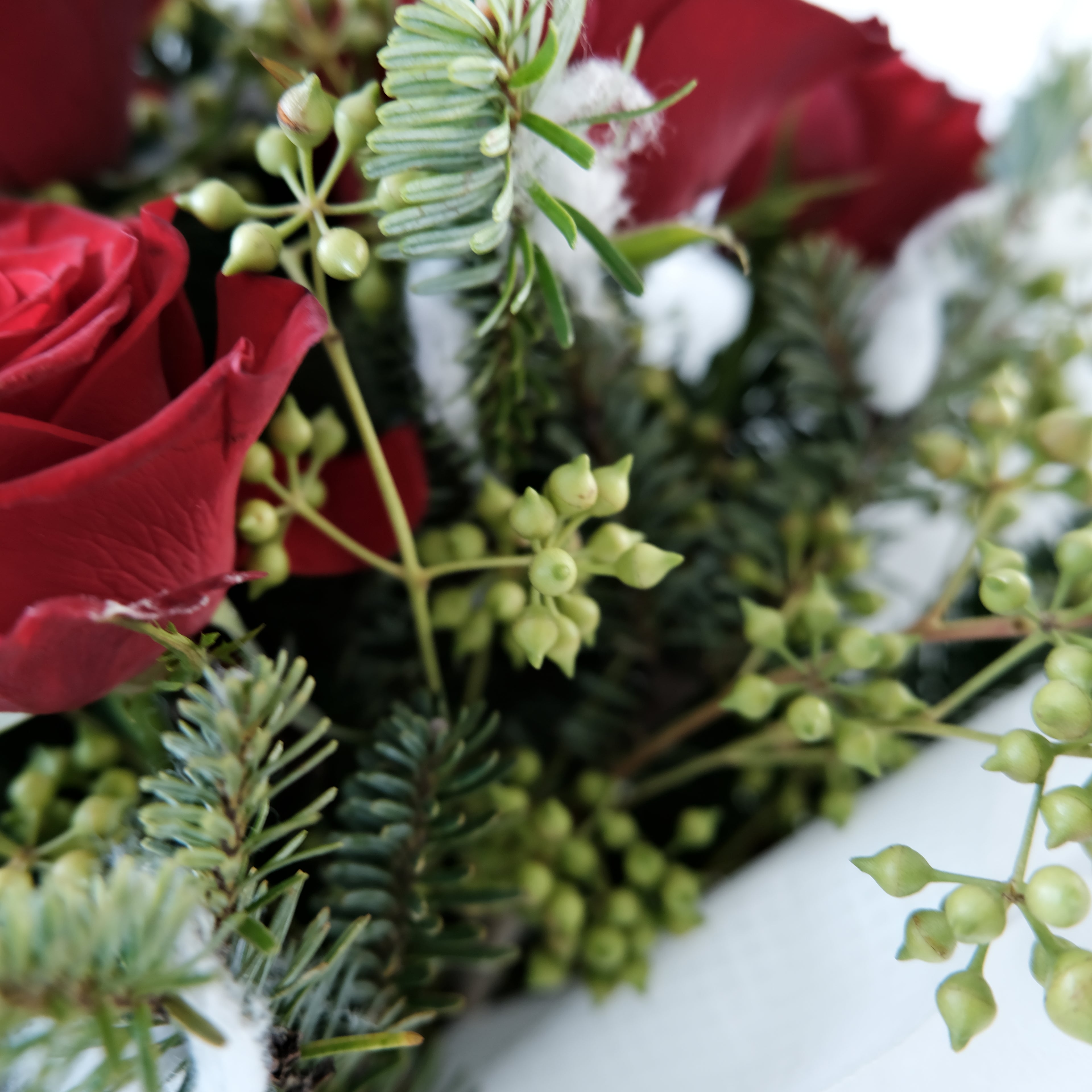 Close-up of a festive wreath with red roses and greenery on a white background