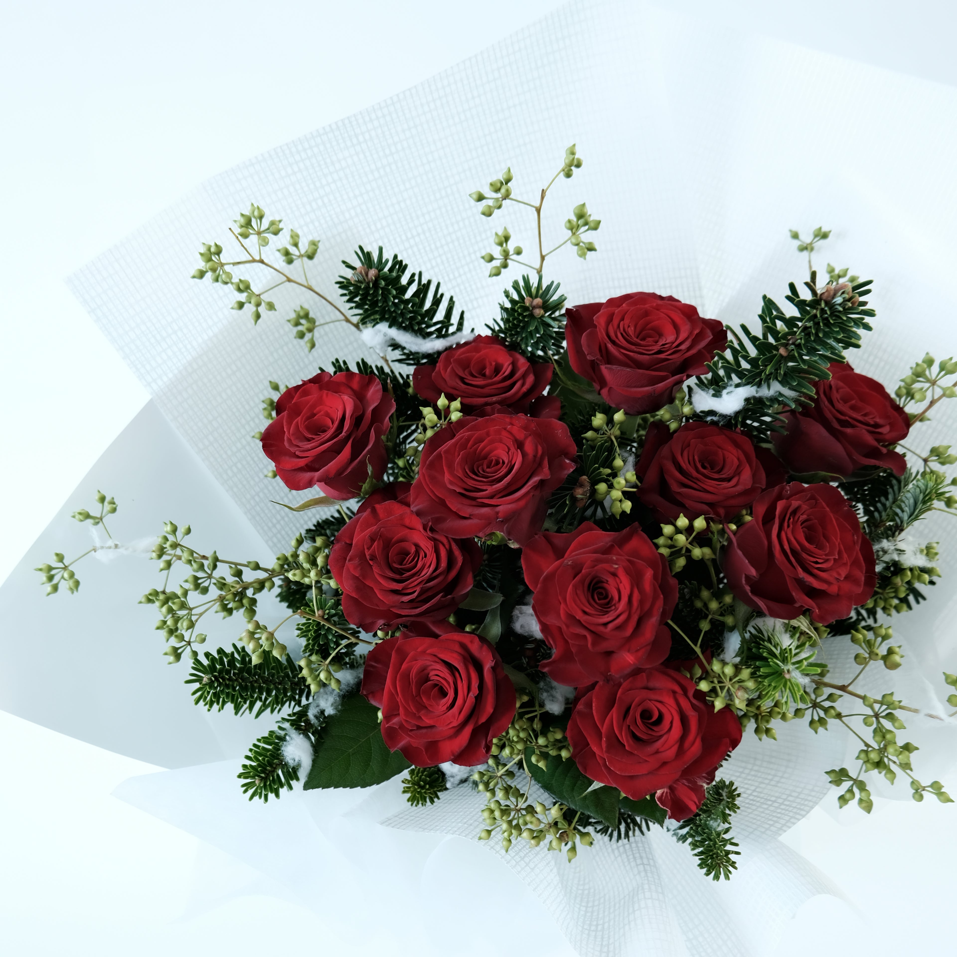 Bouquet of red roses with greenery on a white background