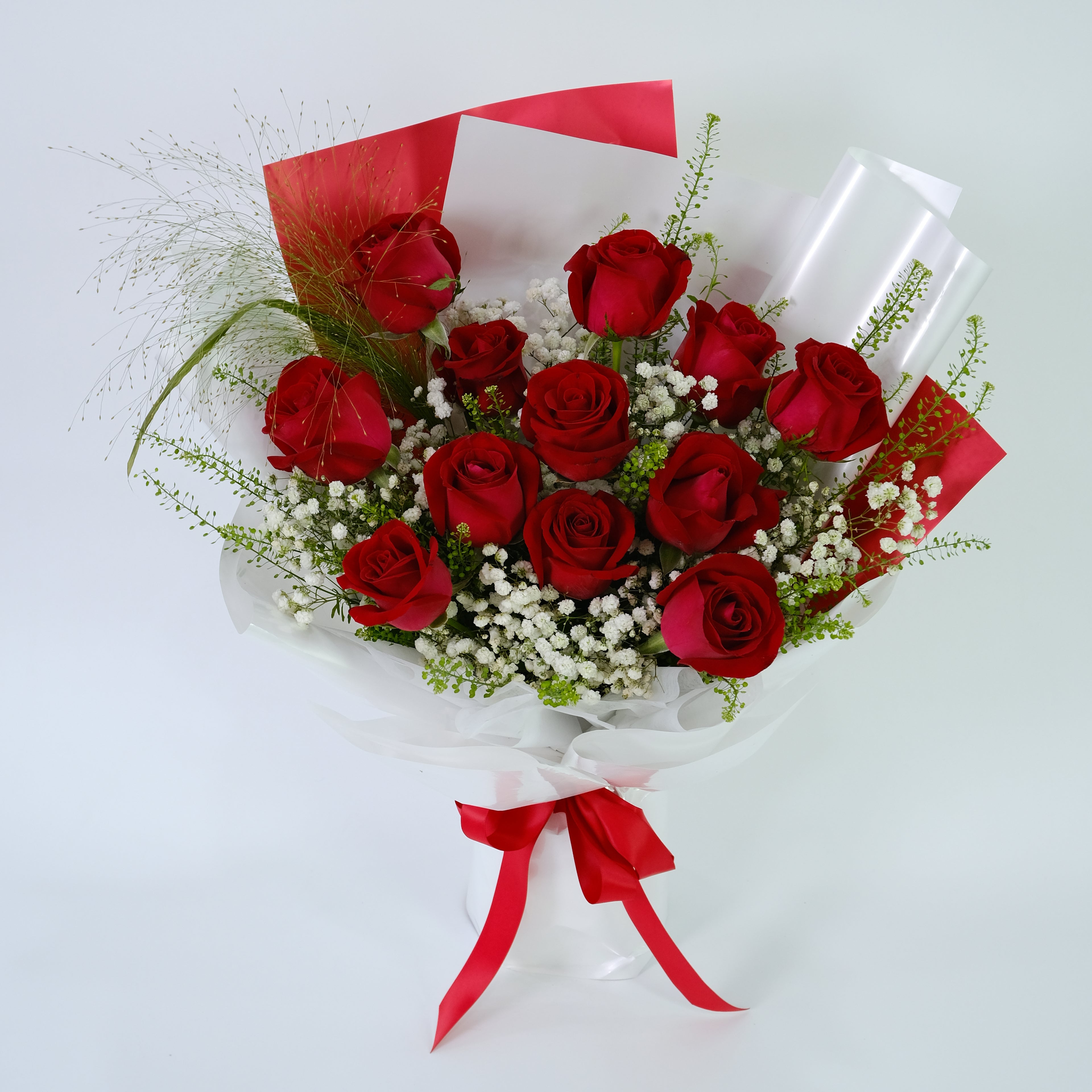Bouquet of red roses with greenery and red ribbons on a white background