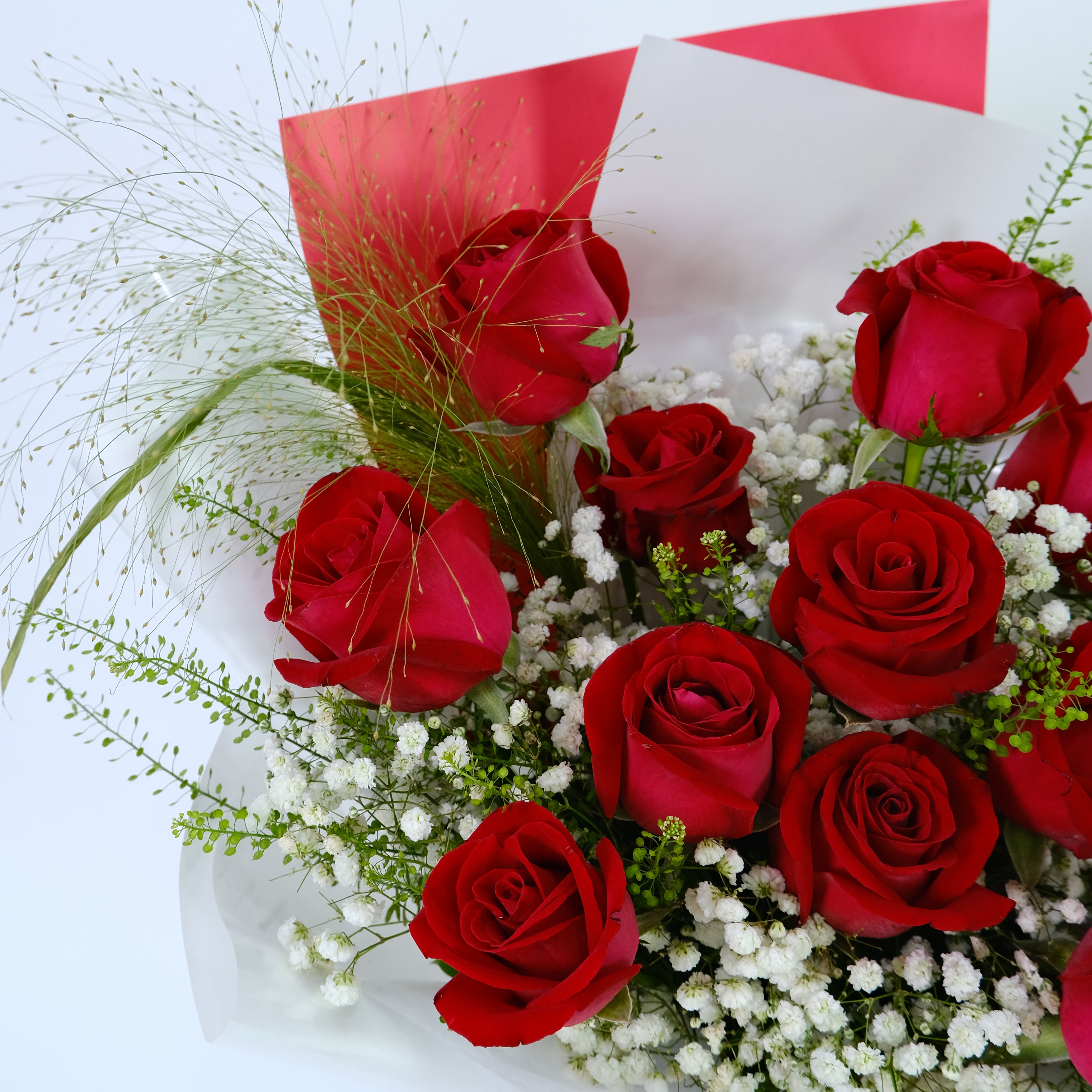 Bouquet of red roses with greenery and white flowers on a white background