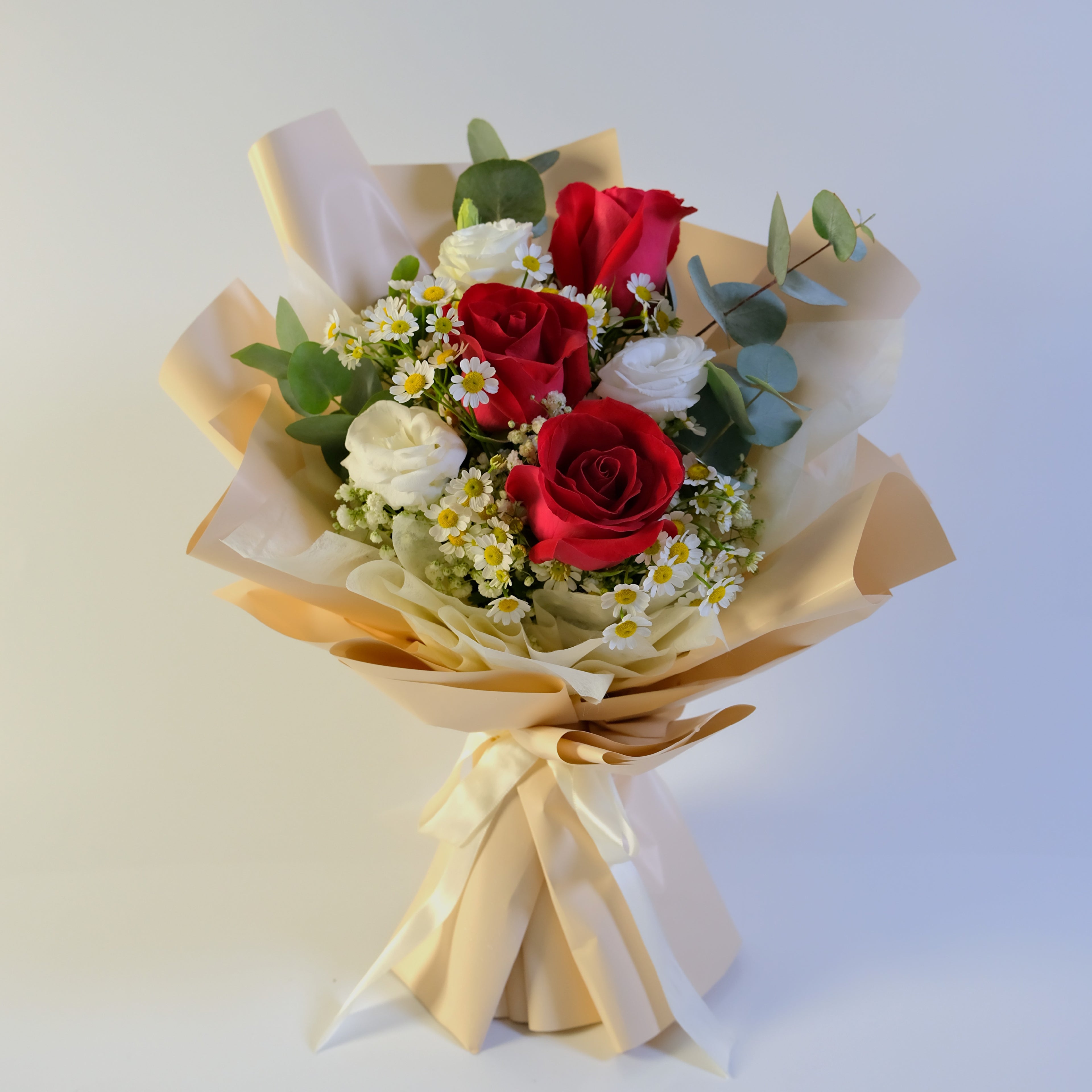 Bouquet of red and white roses with greenery on a light background