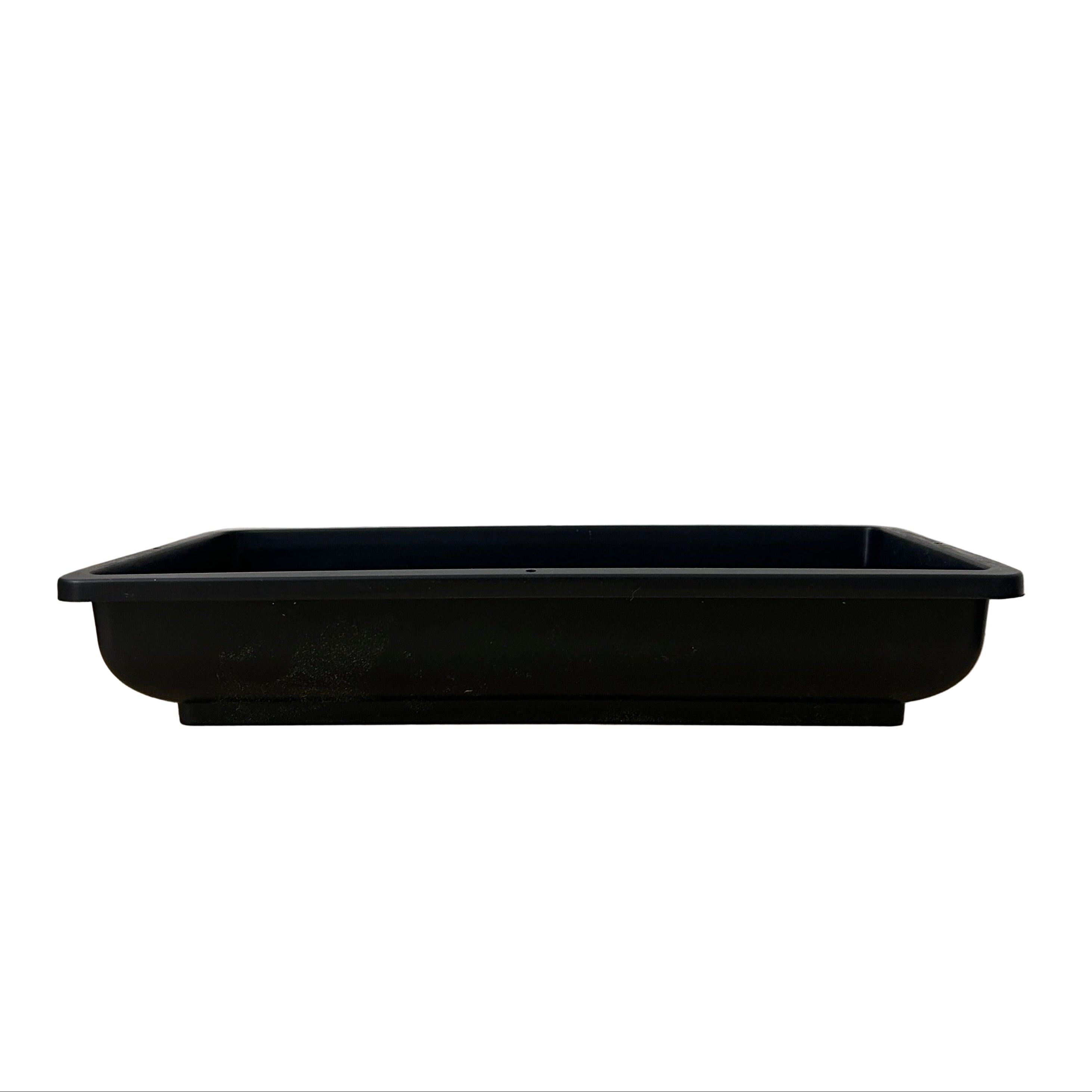 Black rectangular plastic tray on a wooden surface with a white wall background