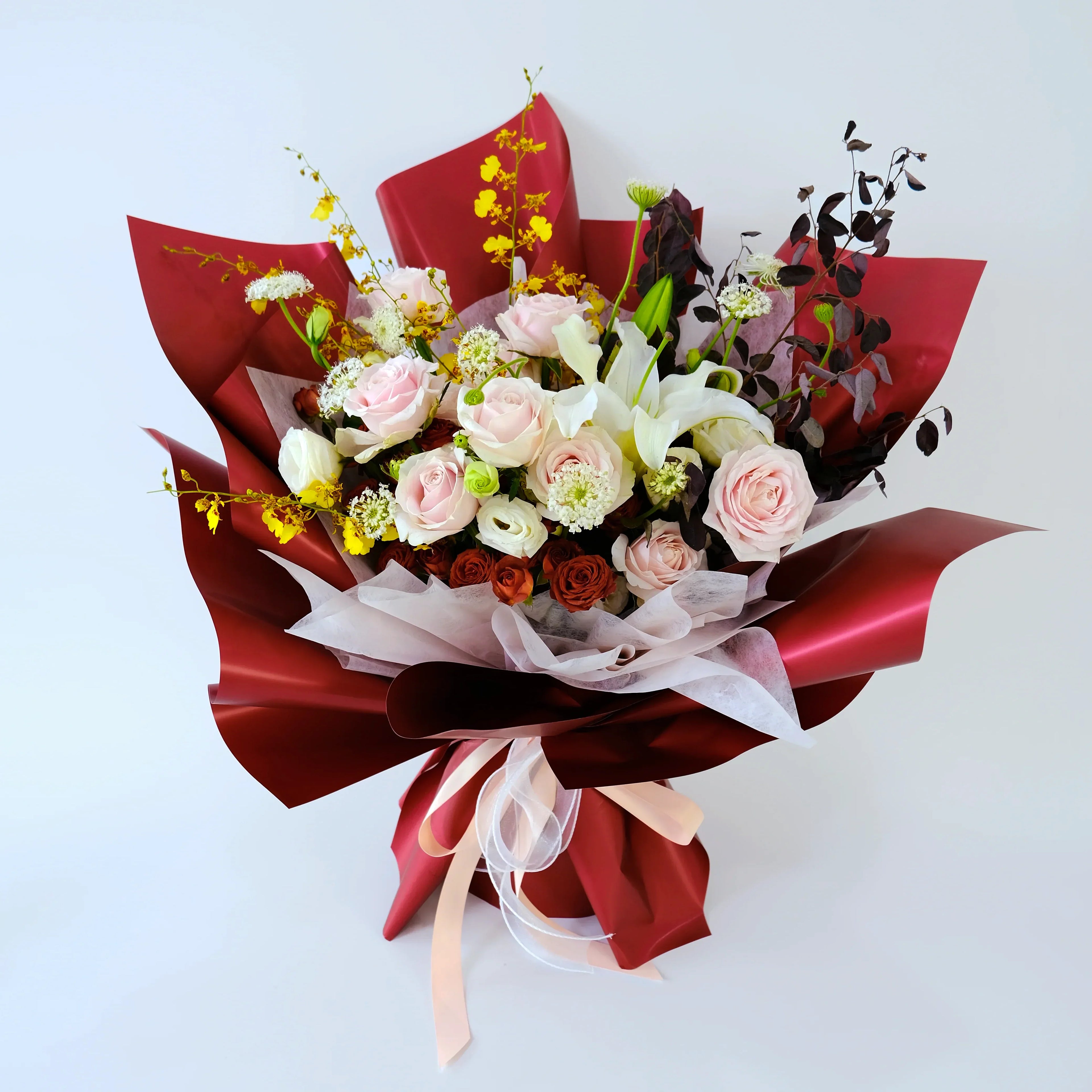 Elegant bouquet with pink roses, lilies and yellow flowers, wrapped in red paper