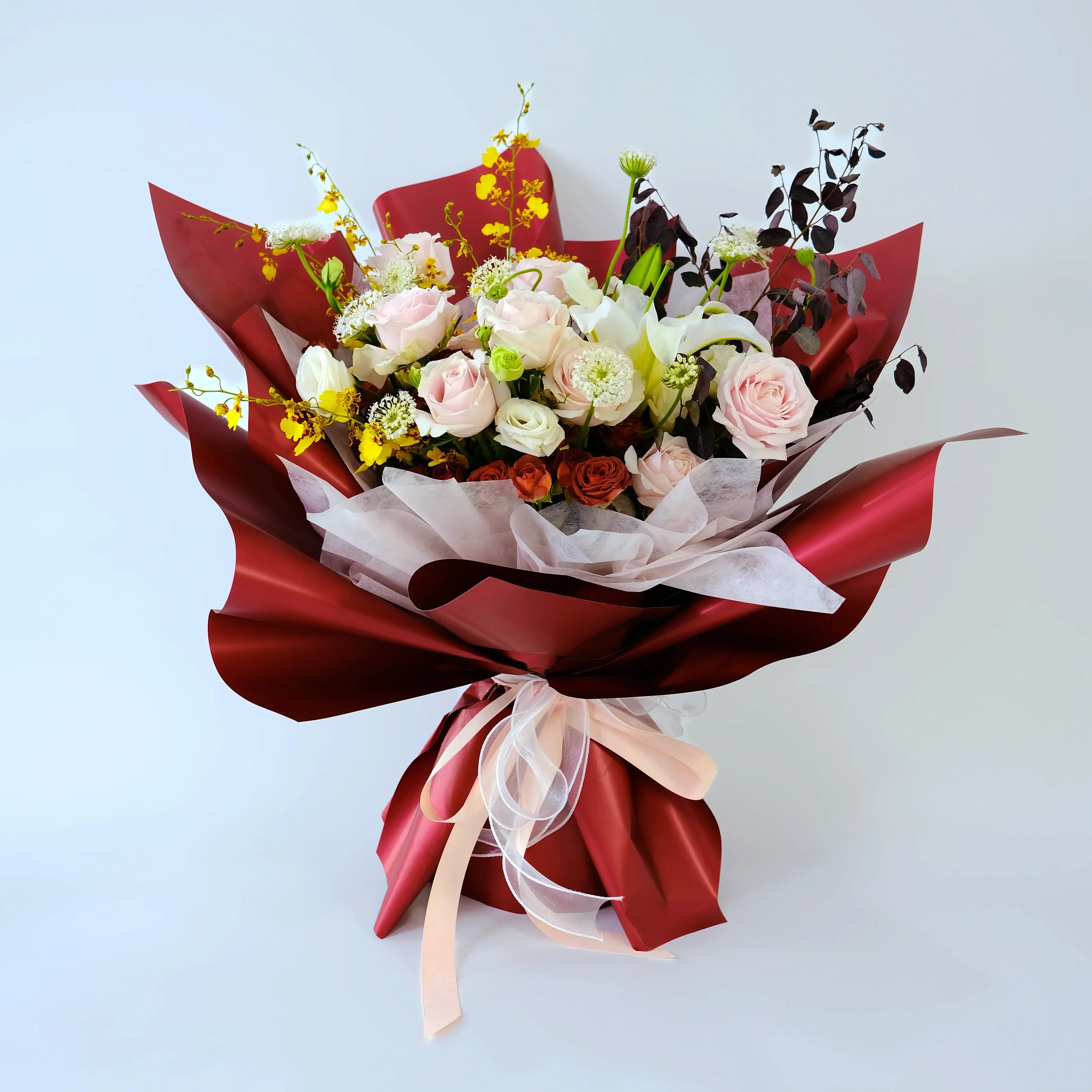 Luxury flower bouquet with pink roses, white lilies and red wrapping on white background