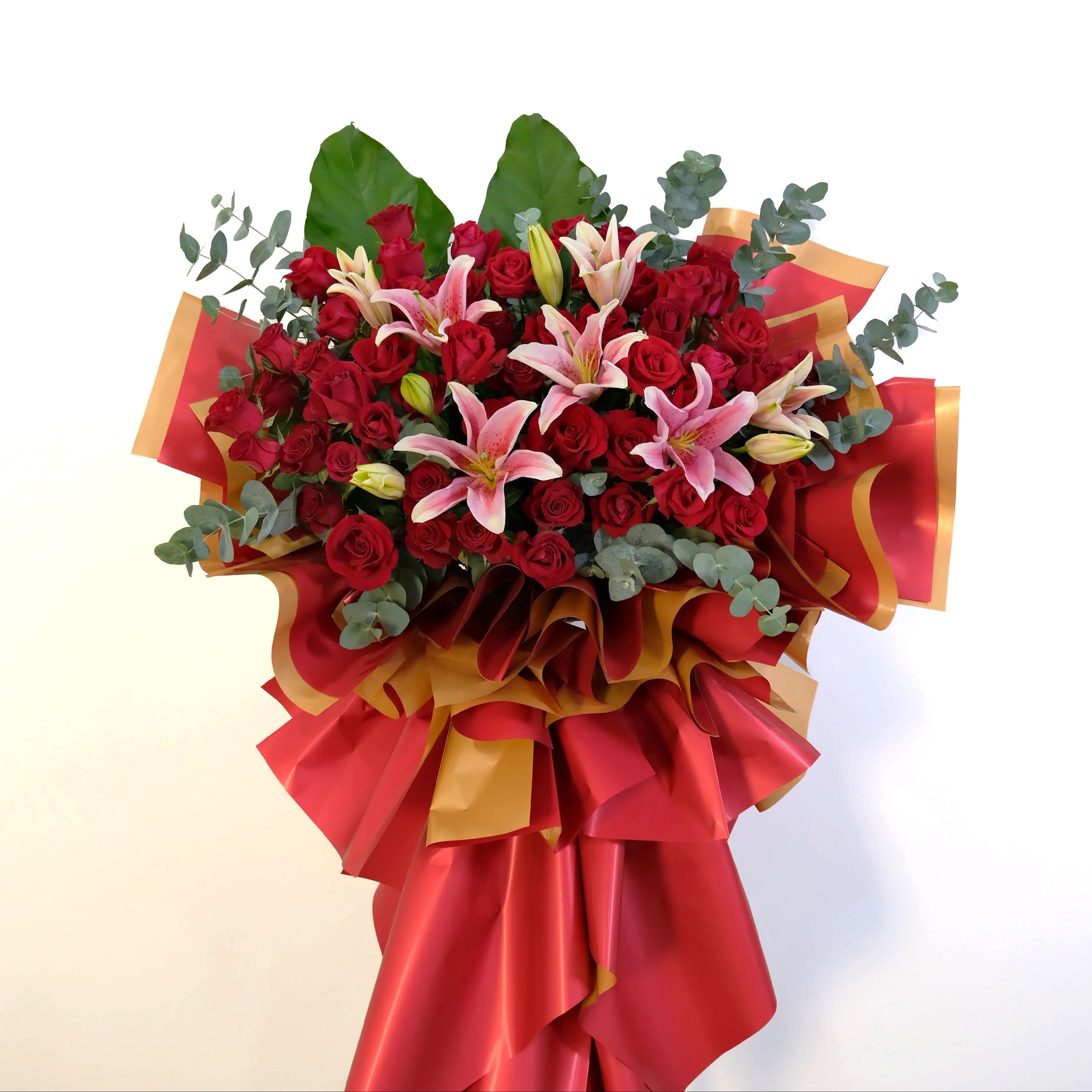 Bouquet of red roses and pink lilies with red and gold ribbons on a white background