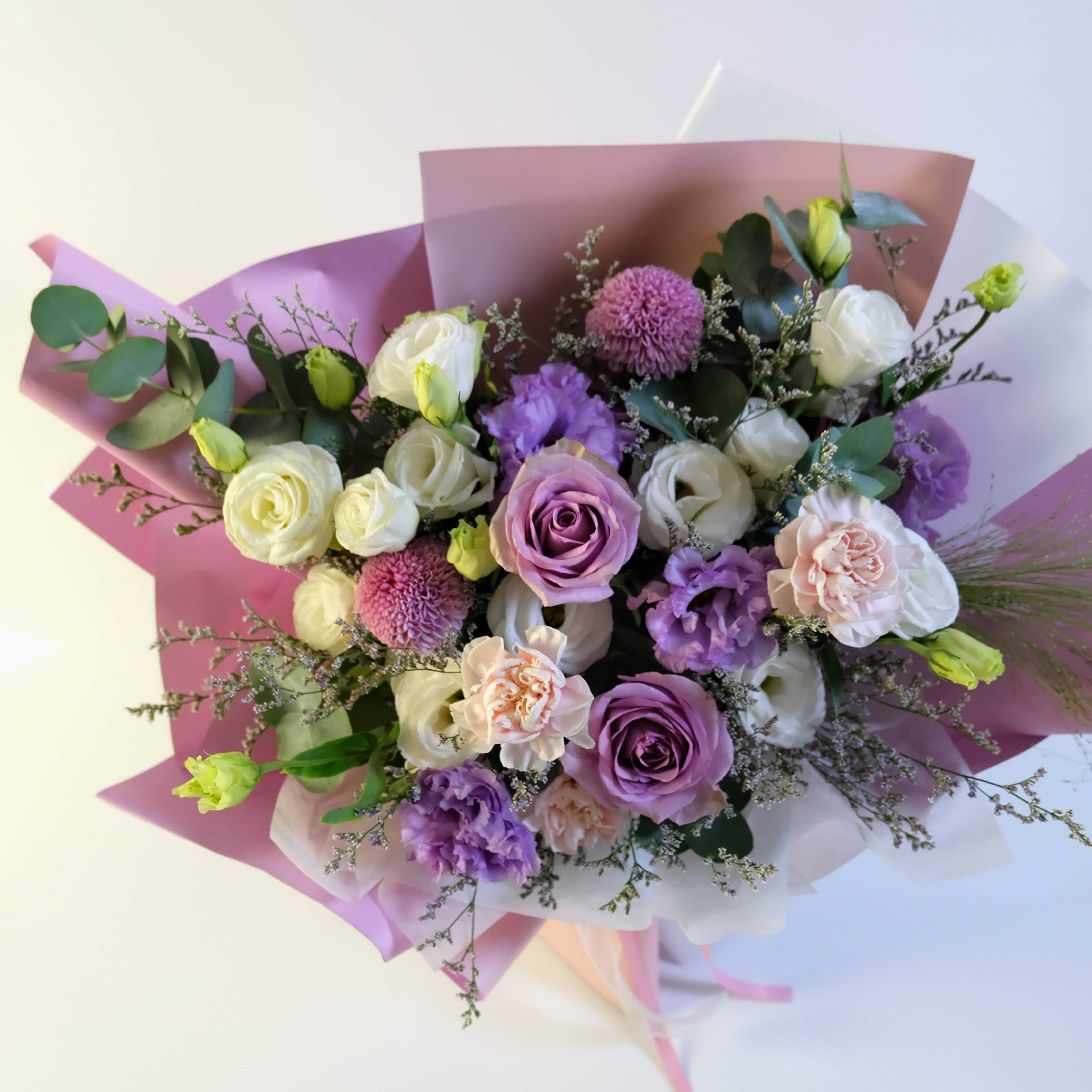 Bouquet of flowers with purple, white, and green colors on a light background