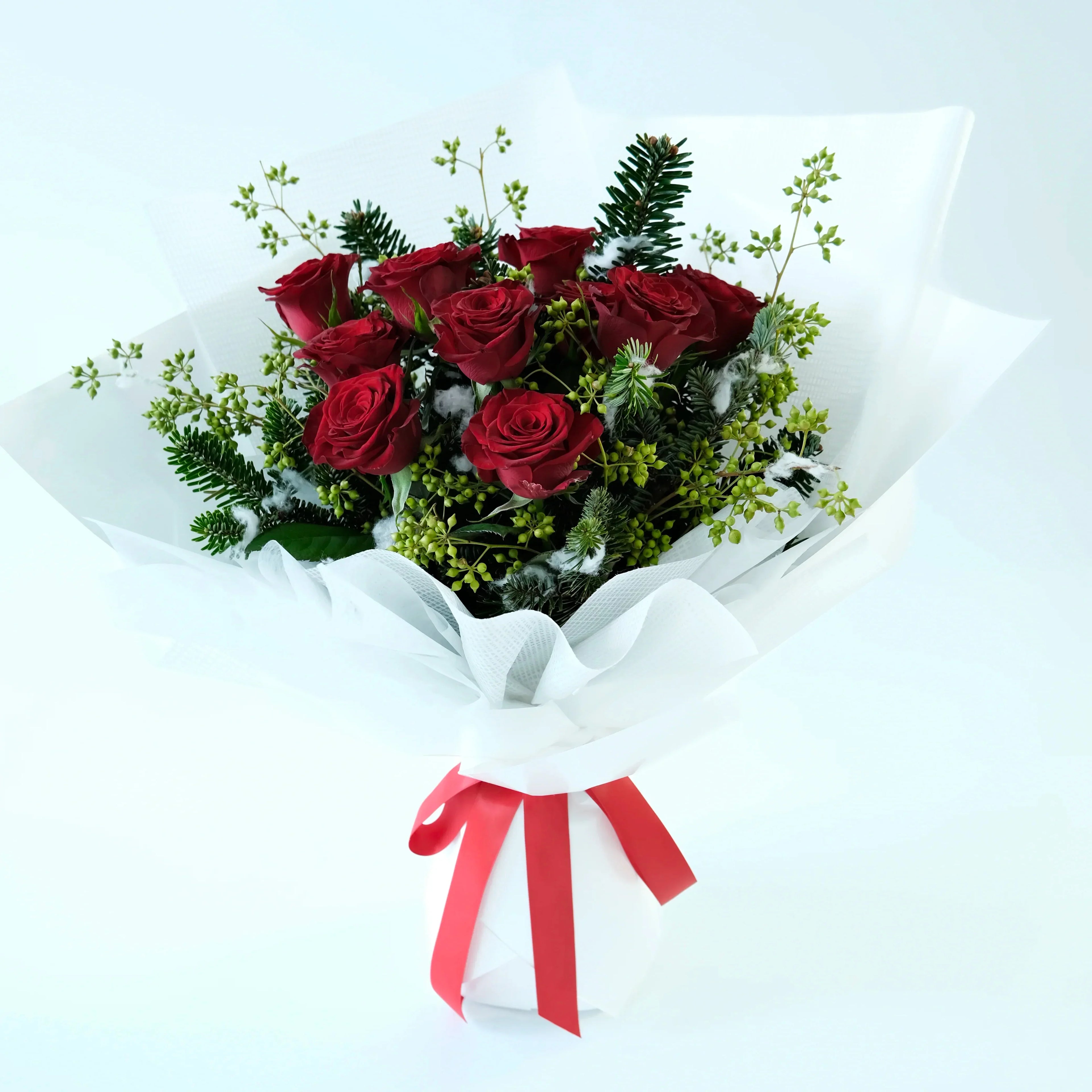 Bouquet of red roses with greenery and a red ribbon on a white background