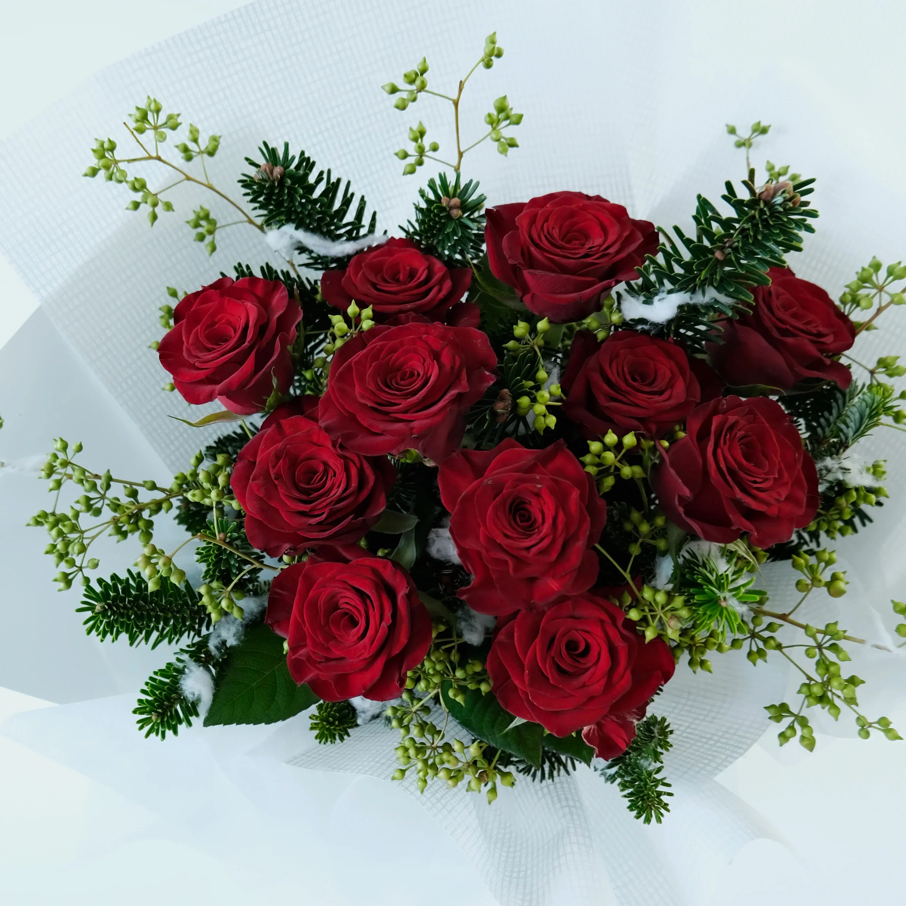 Bouquet of red roses with greenery on a white background