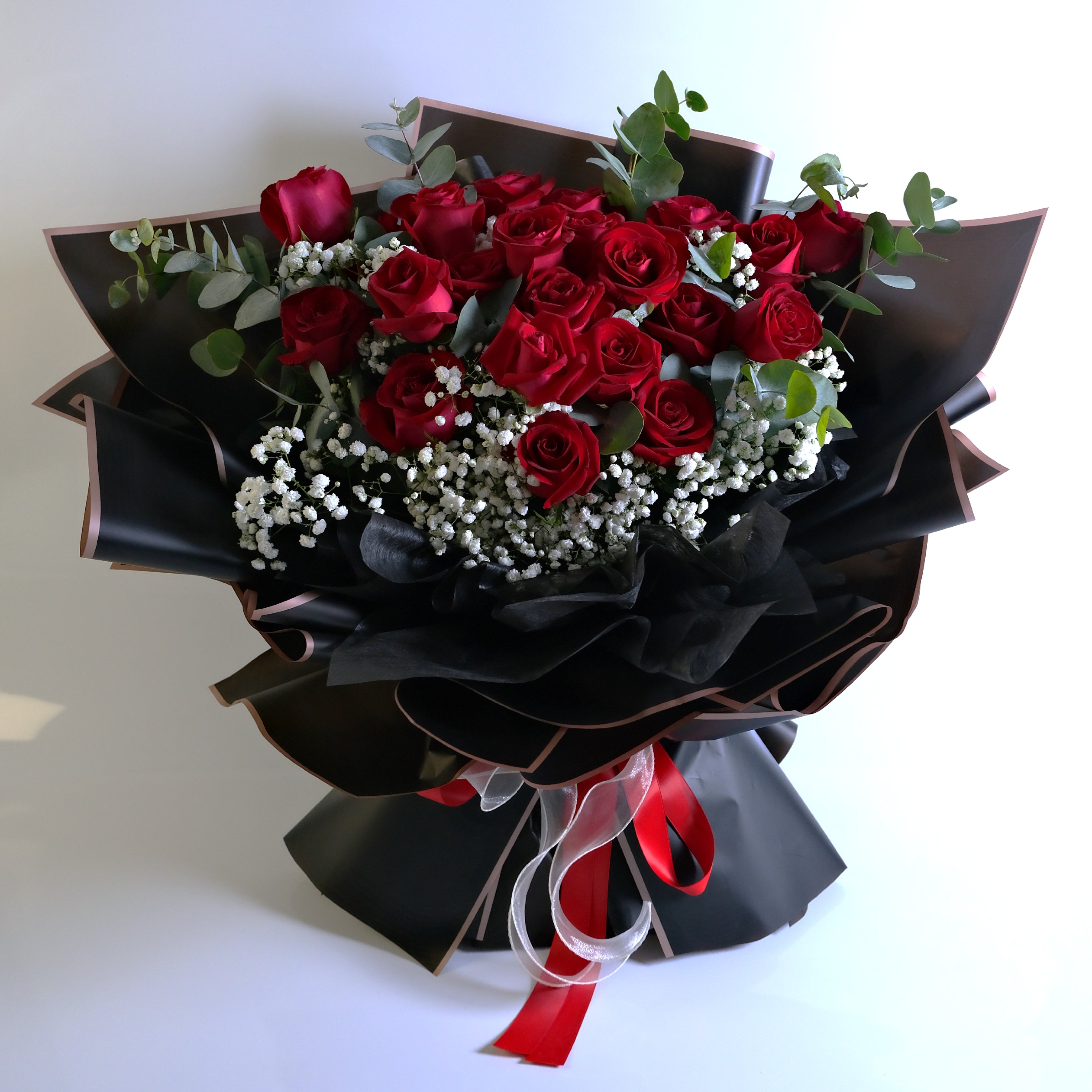 Bouquet of red roses with black and white accents on a light background