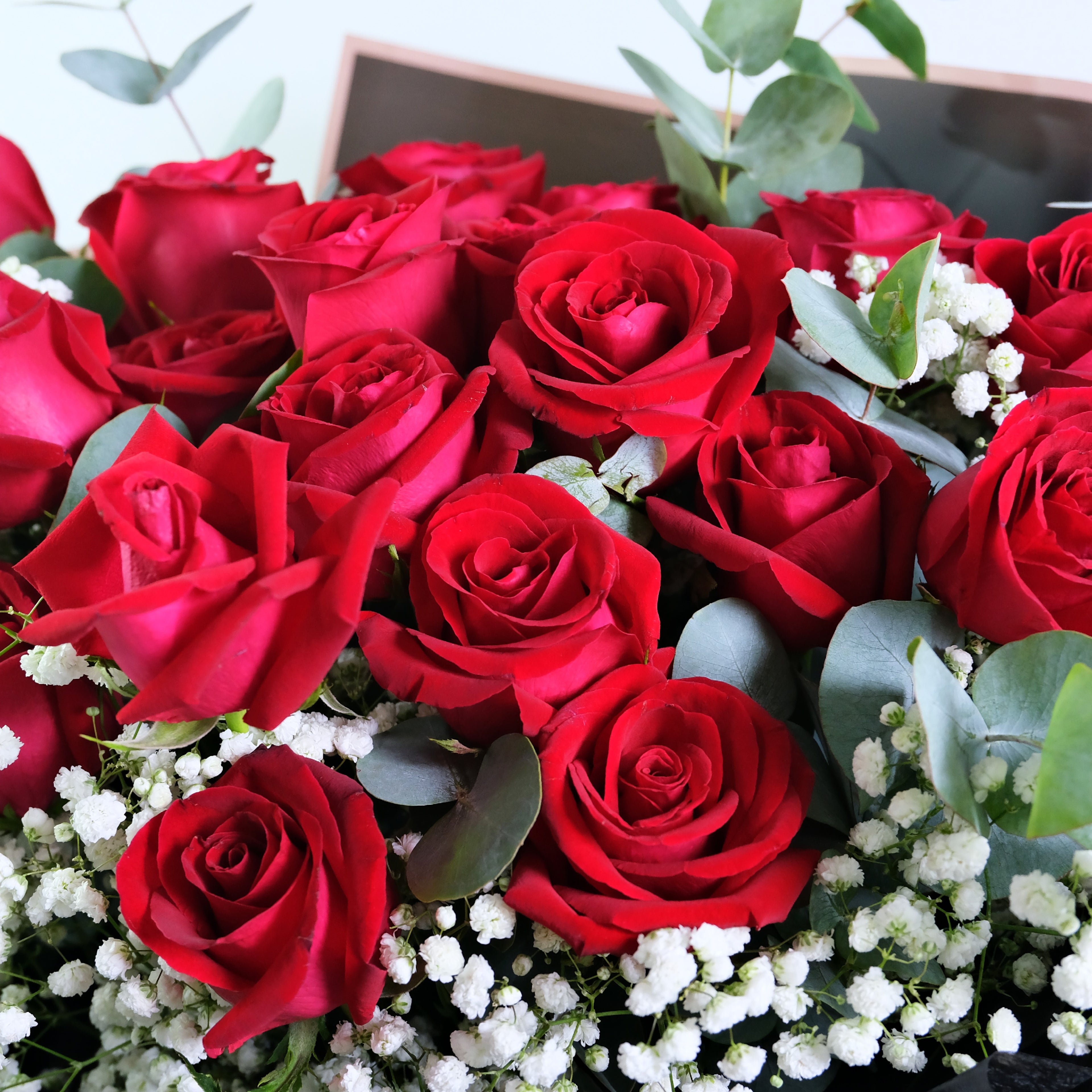 Bouquet of red roses with some greenery and white flowers.