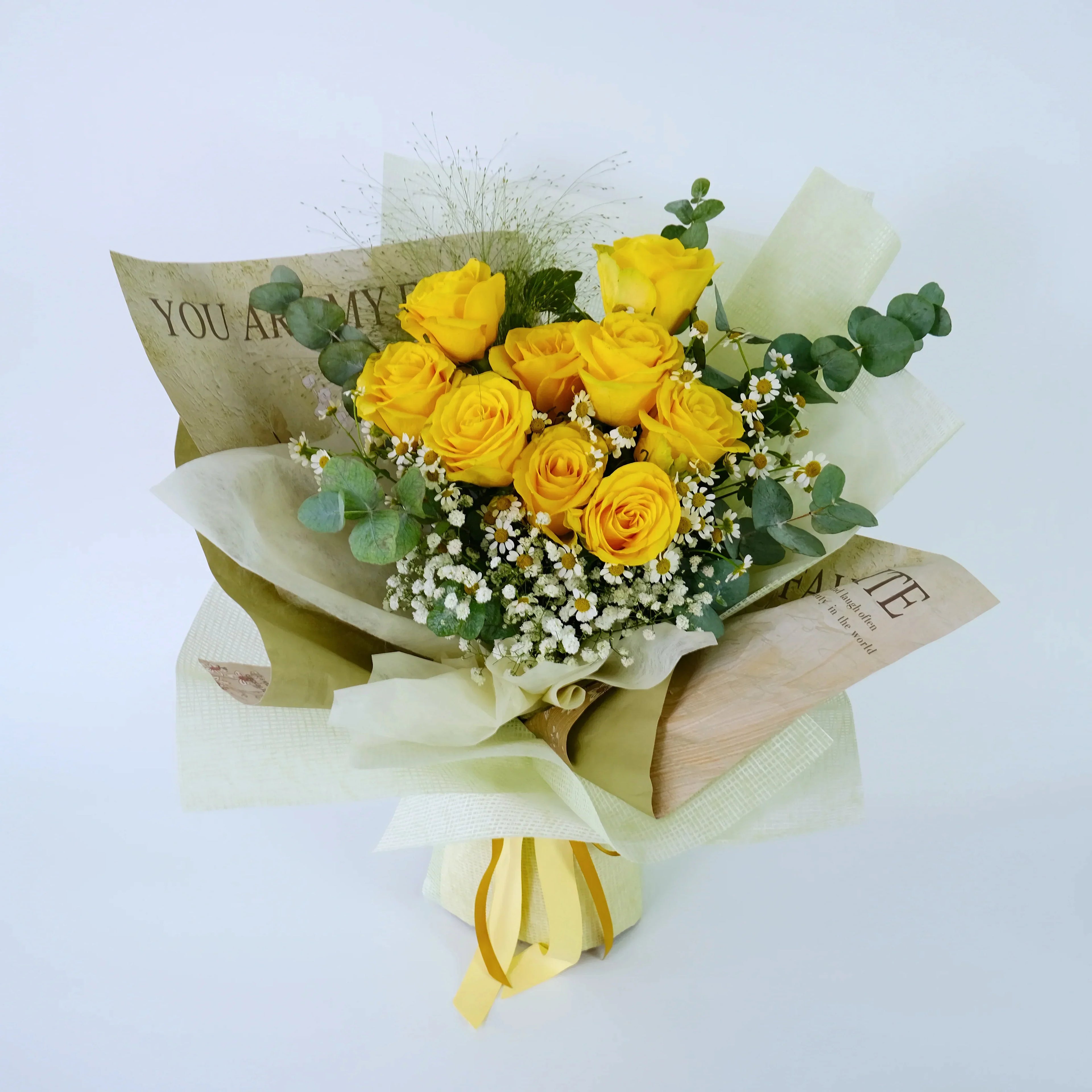 Bouquet of fresh yellow roses with greenery, baby's breath, and decorative wrapping