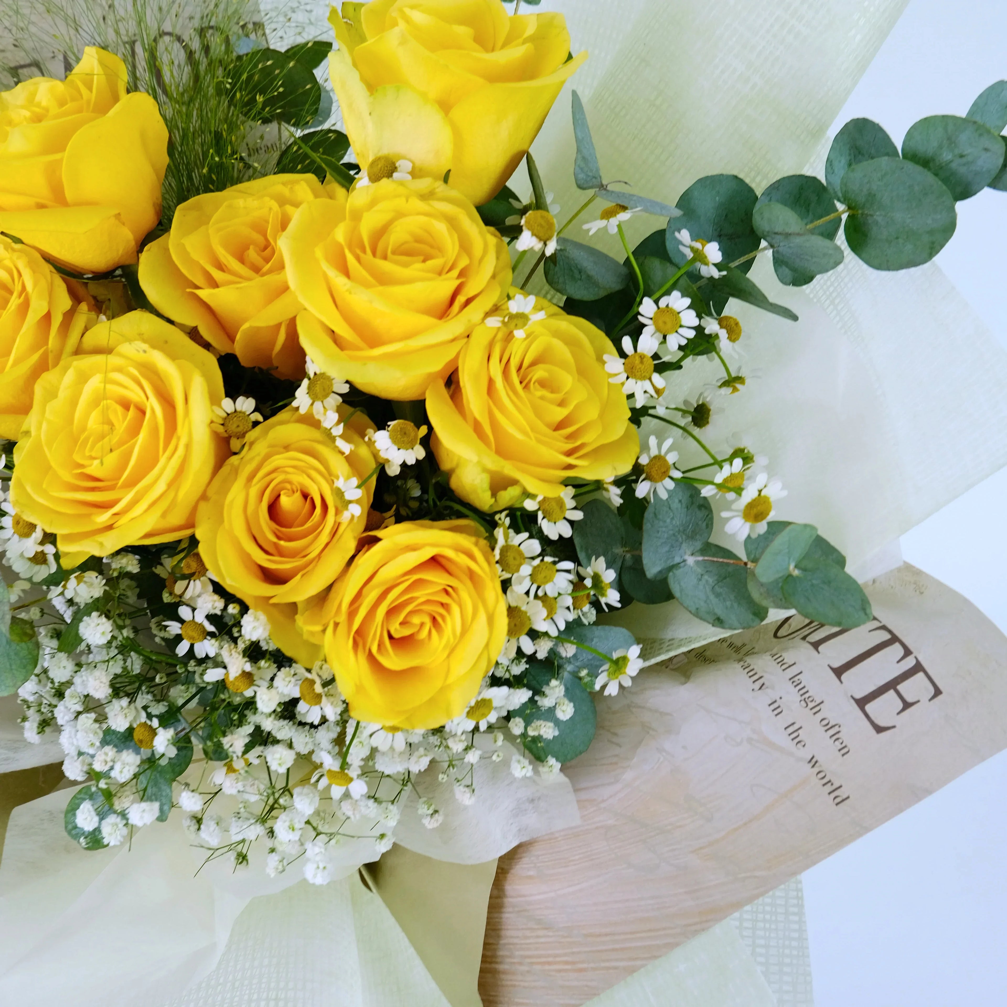 Yellow rose bouquet with white daisies and eucalyptus wrapped in paper