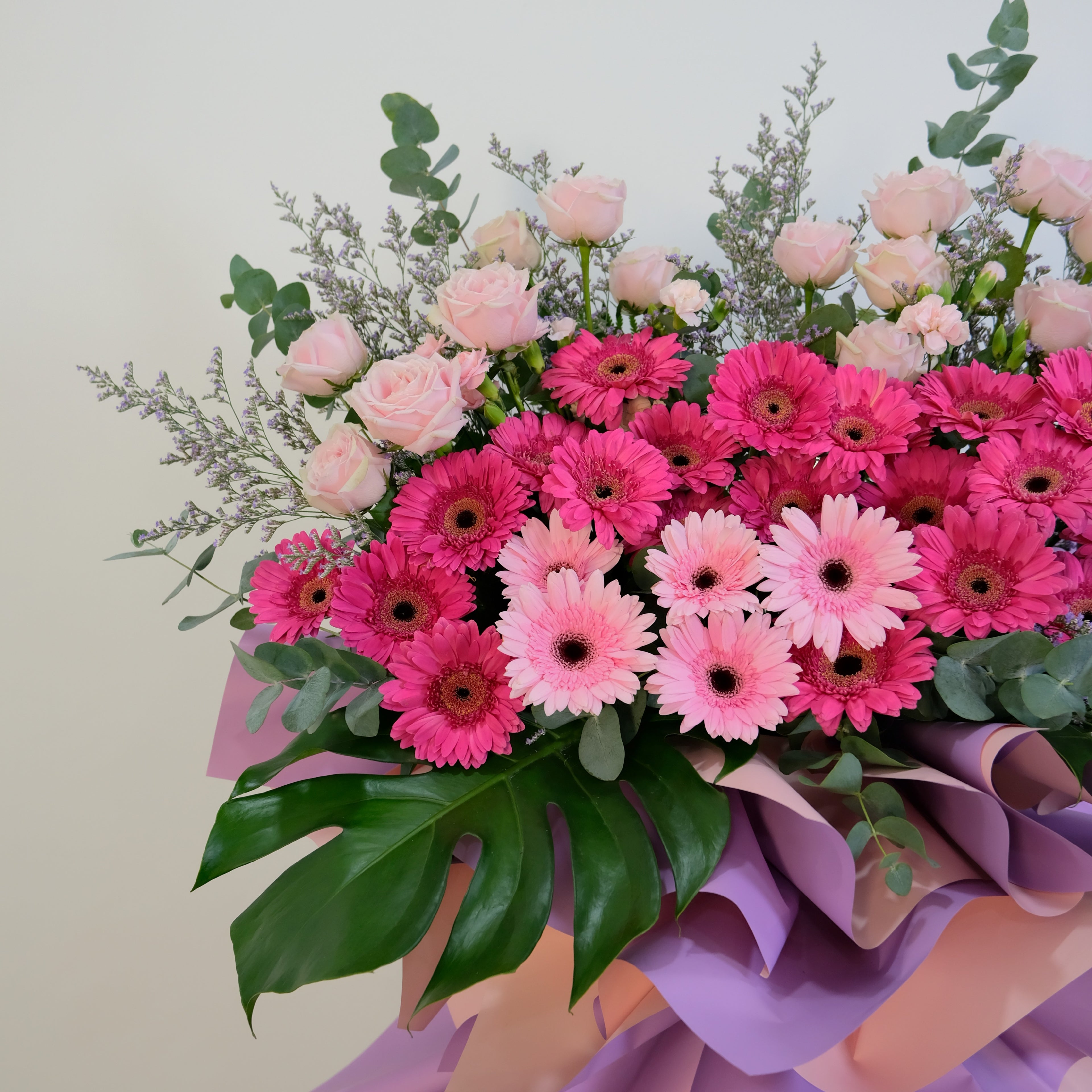 Bouquet of pink and magenta flowers with greenery on a light background