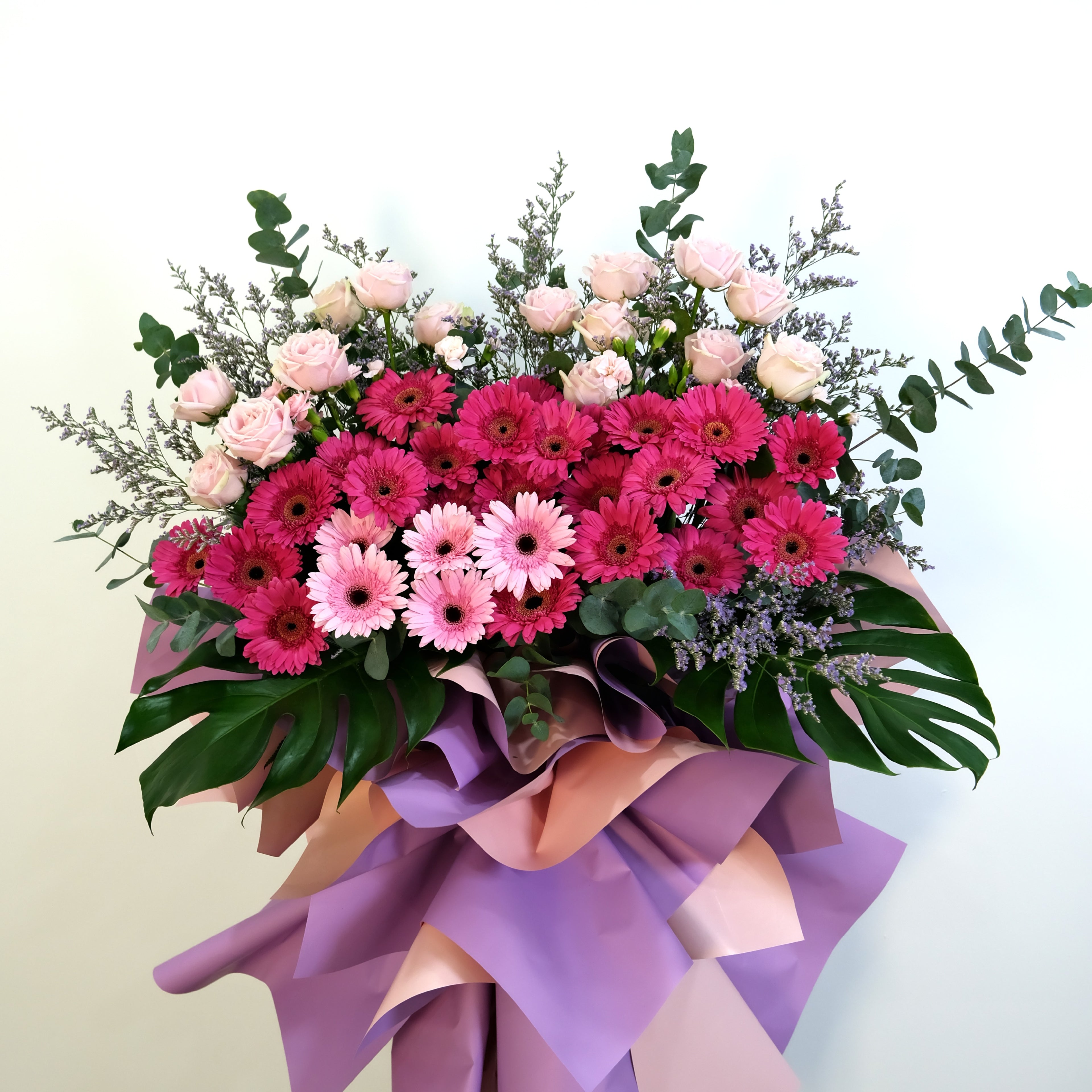 Grand opening flower stand with pink and purple flowers with greenery on a light background