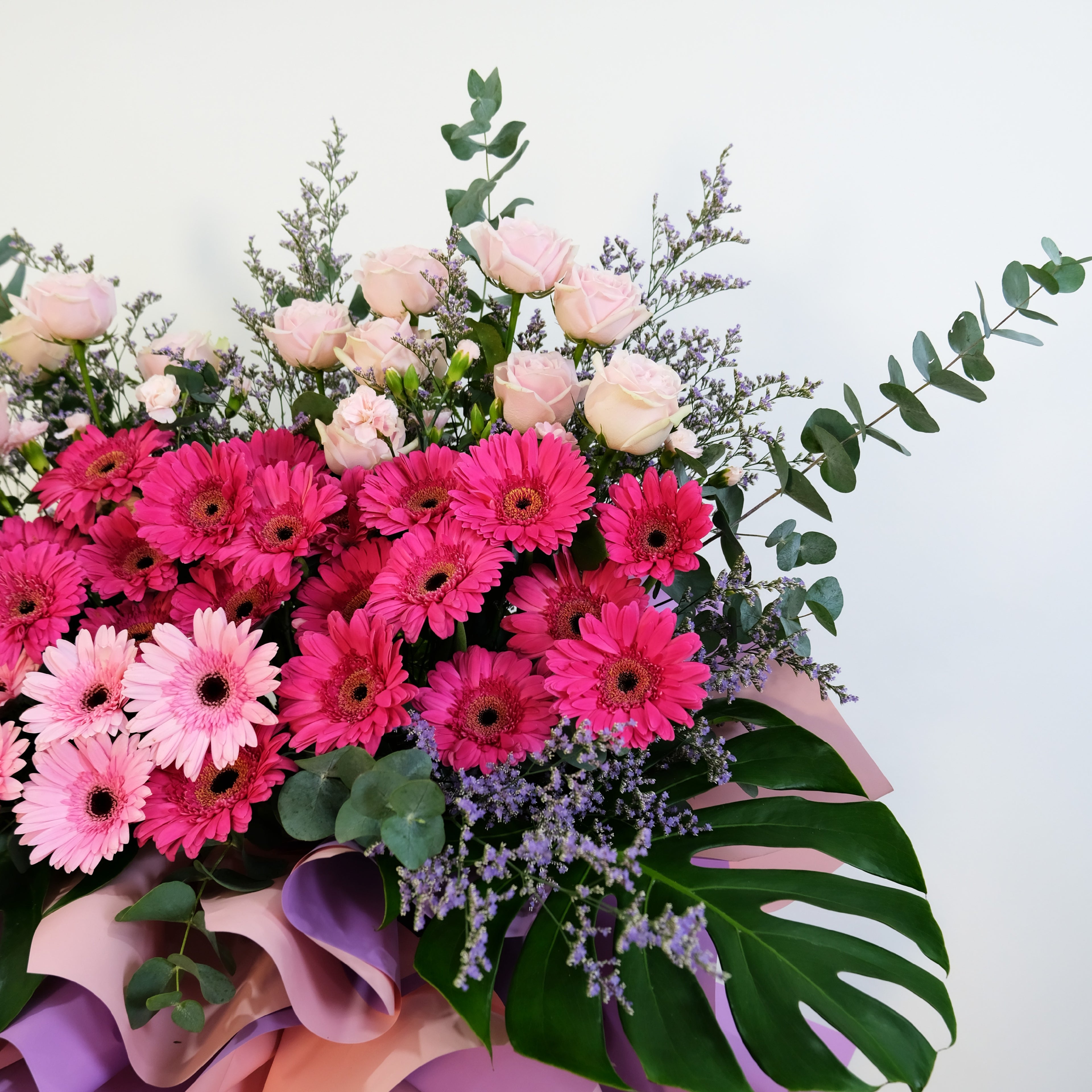 grand opening Bouquet of pink and red flowers with green leaves on a white background