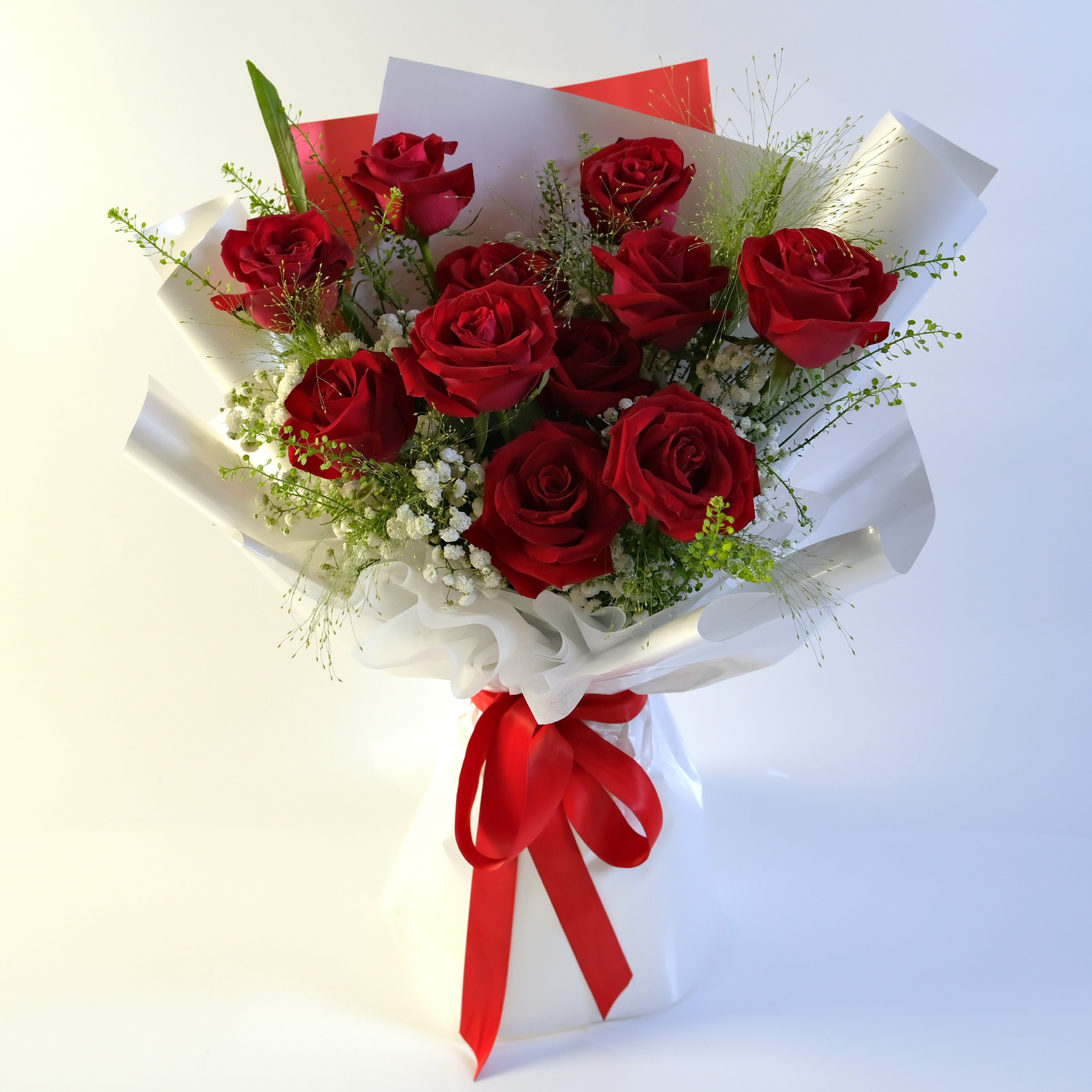 Bouquet of red roses with white paper and red ribbons on a light gray background