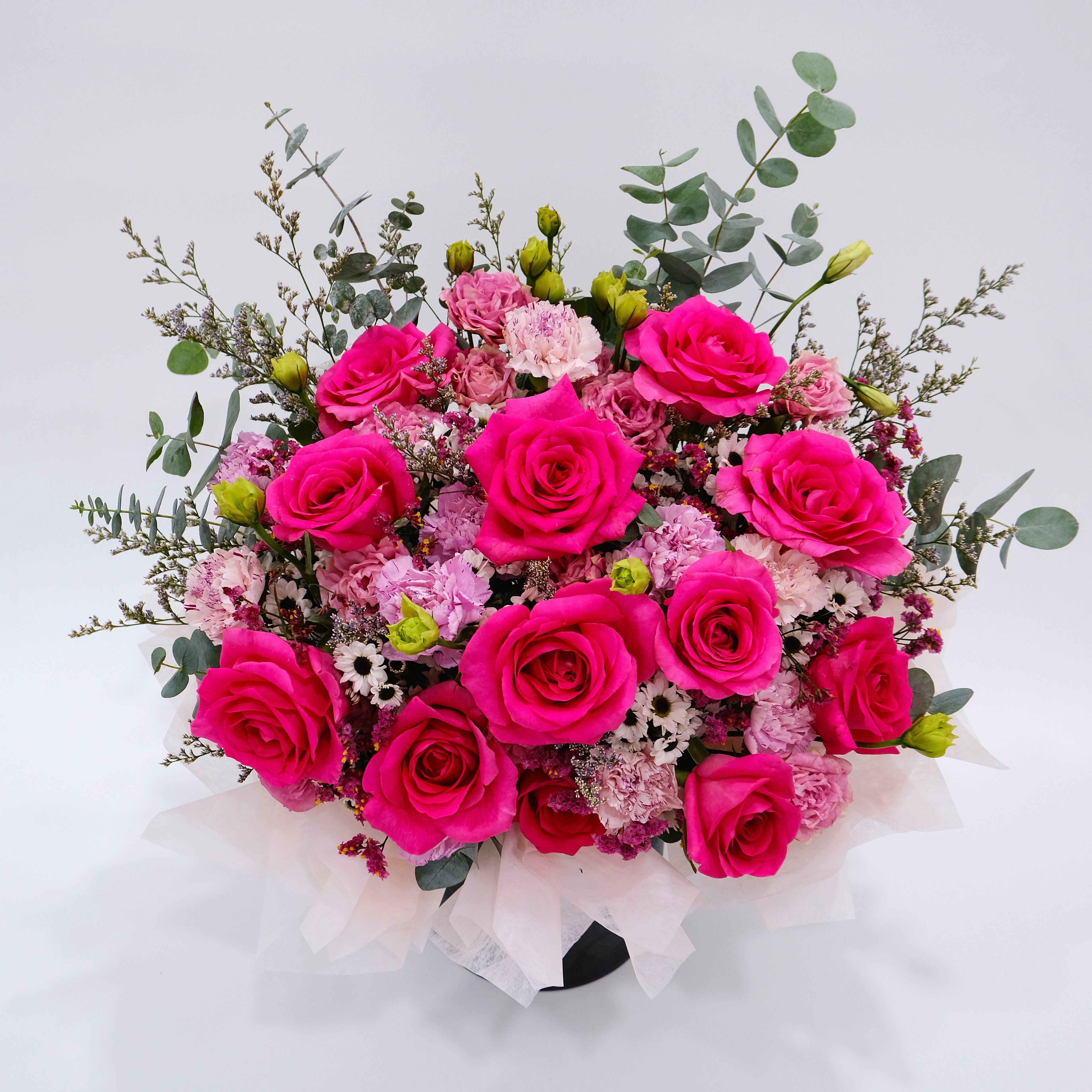 Bouquet of pink and red roses with greenery on a light gray background