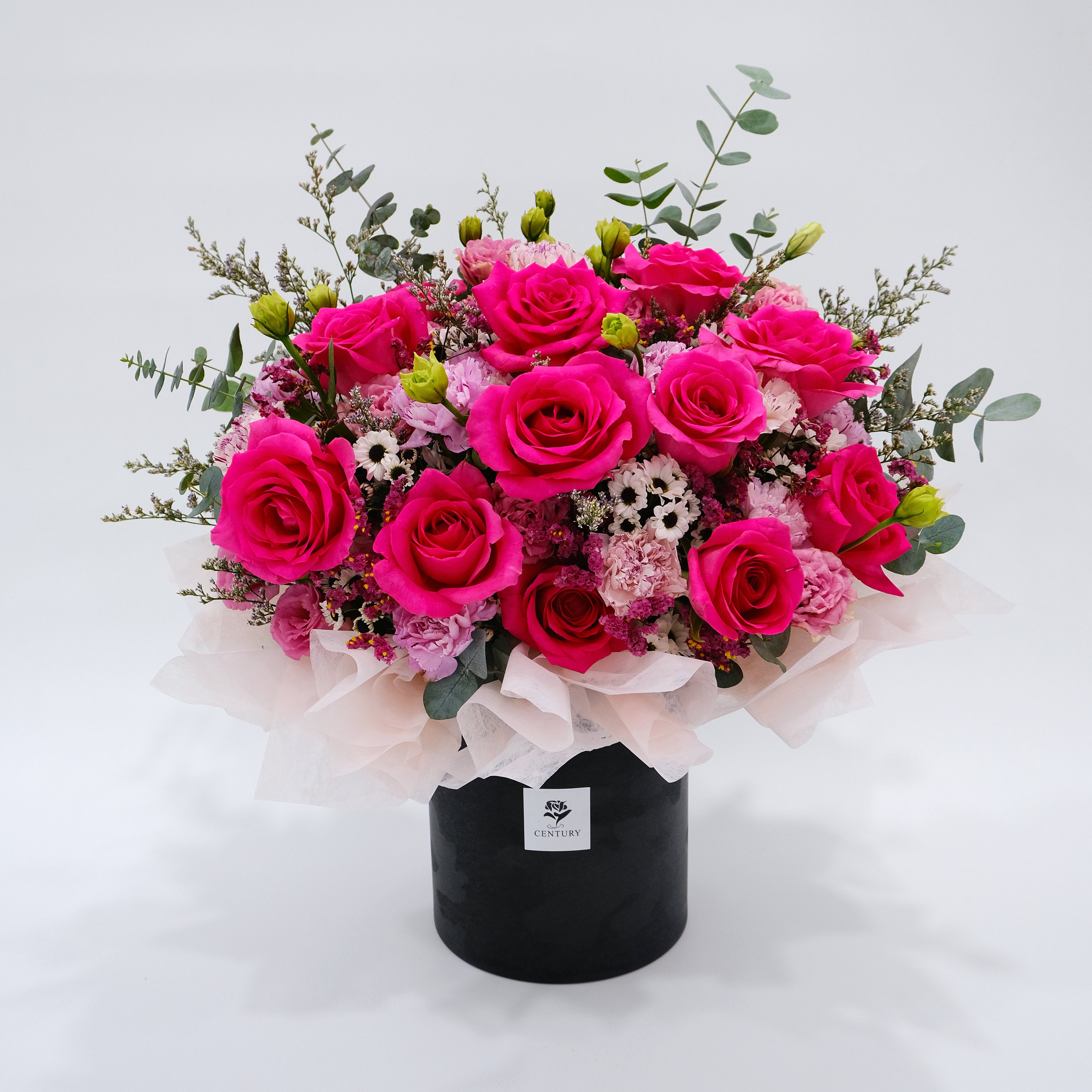 Bouquet of pink roses and greenery in a black box on a white background