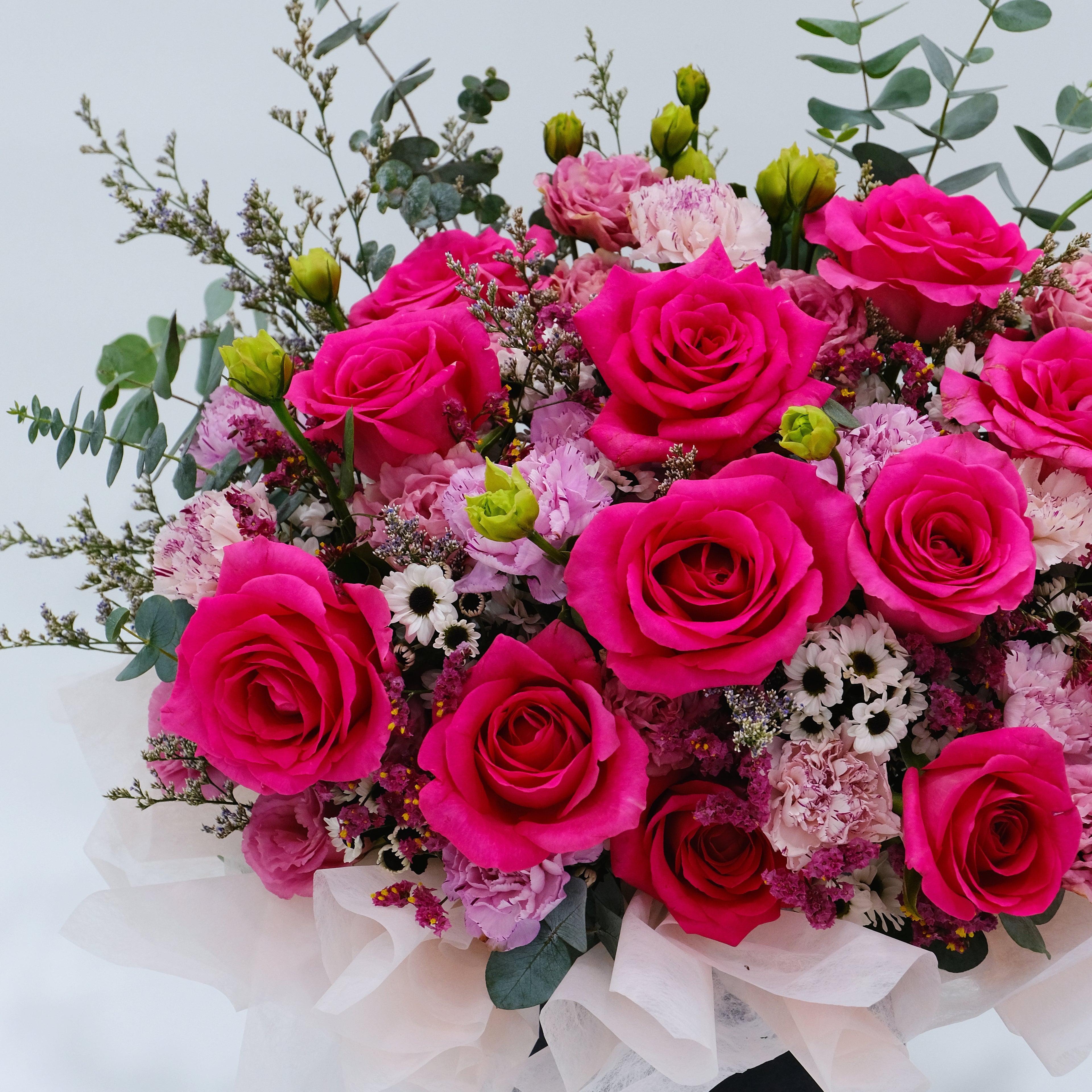 Bouquet of pink and green flowers with a white ribbon on a light background
