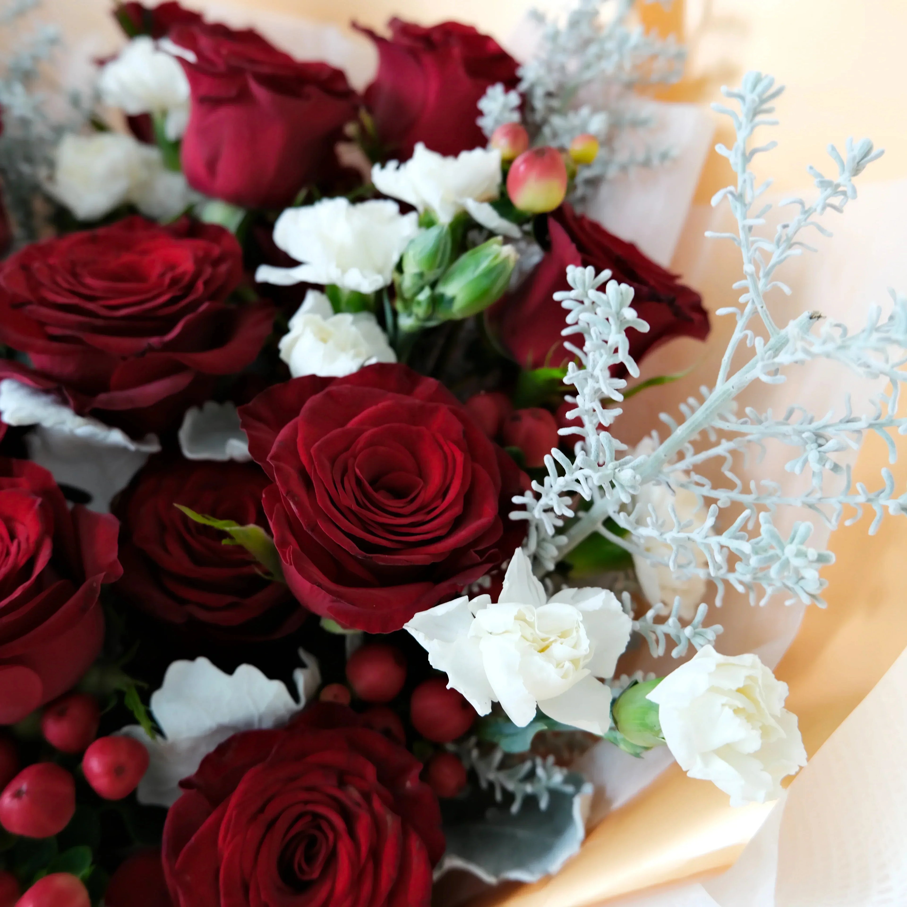 Bouquet of red and white flowers with berries on a wooden surface