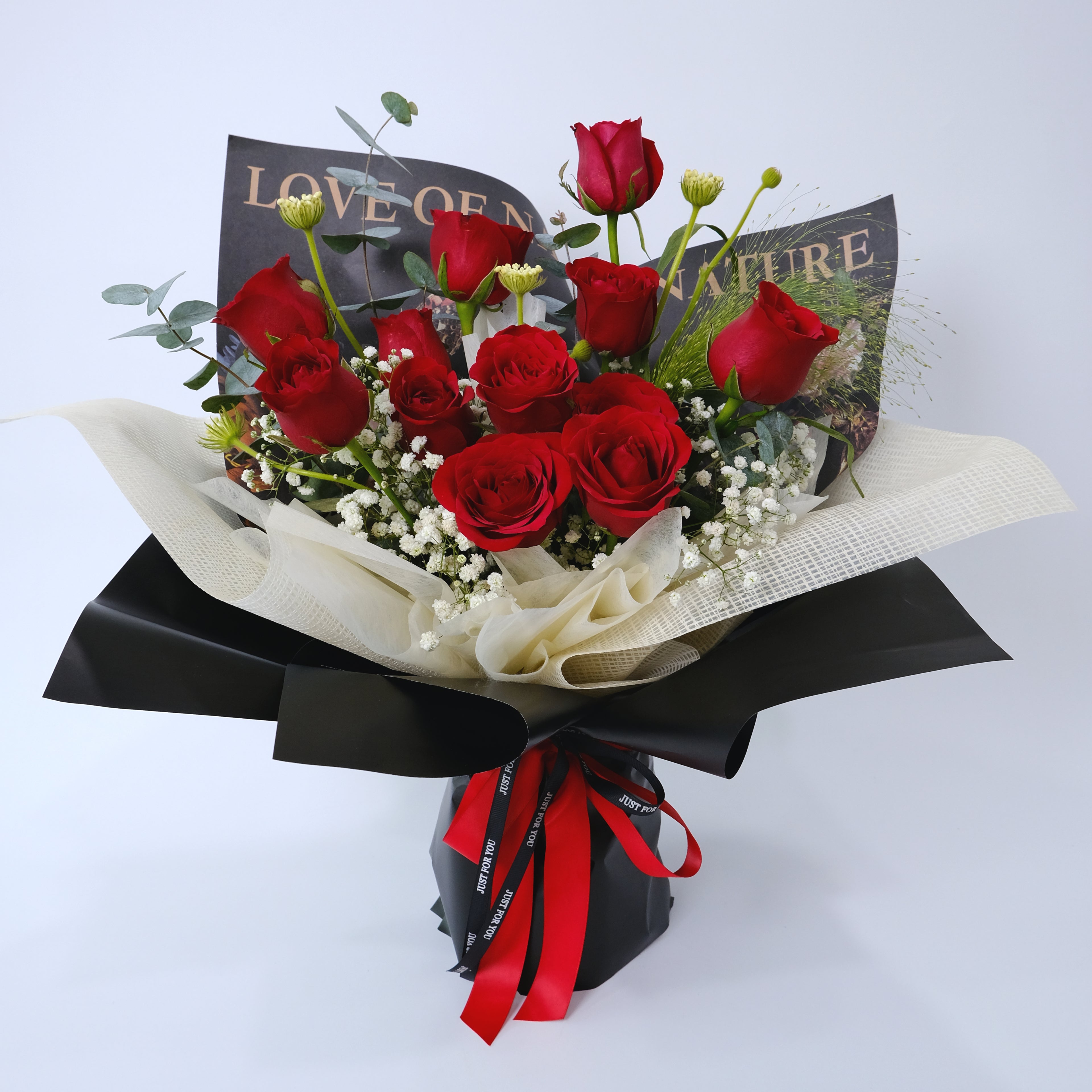 Bouquet of red roses with a black bow and ribbons on a light gray background