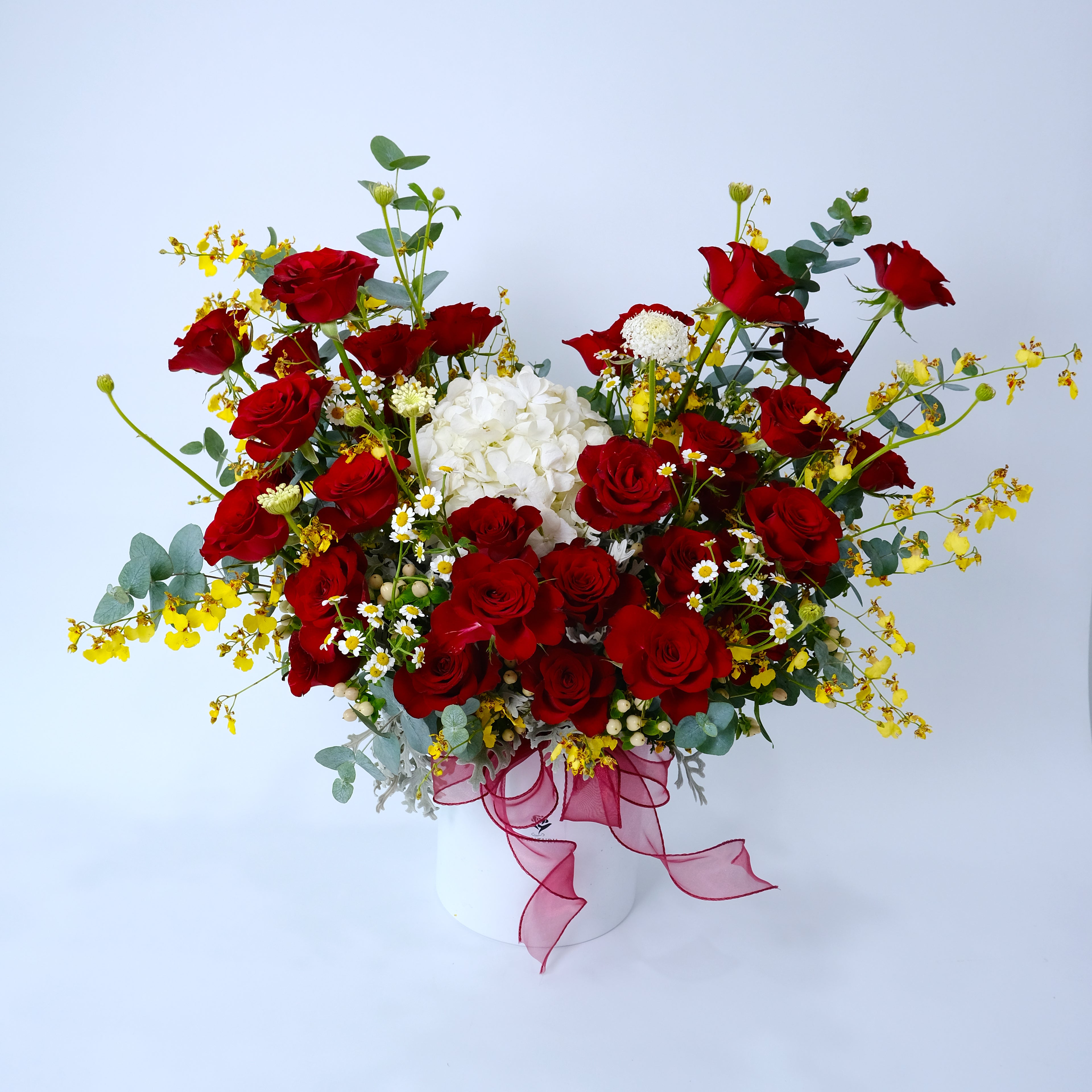 Bouquet of red and white flowers with greenery on a light blue background