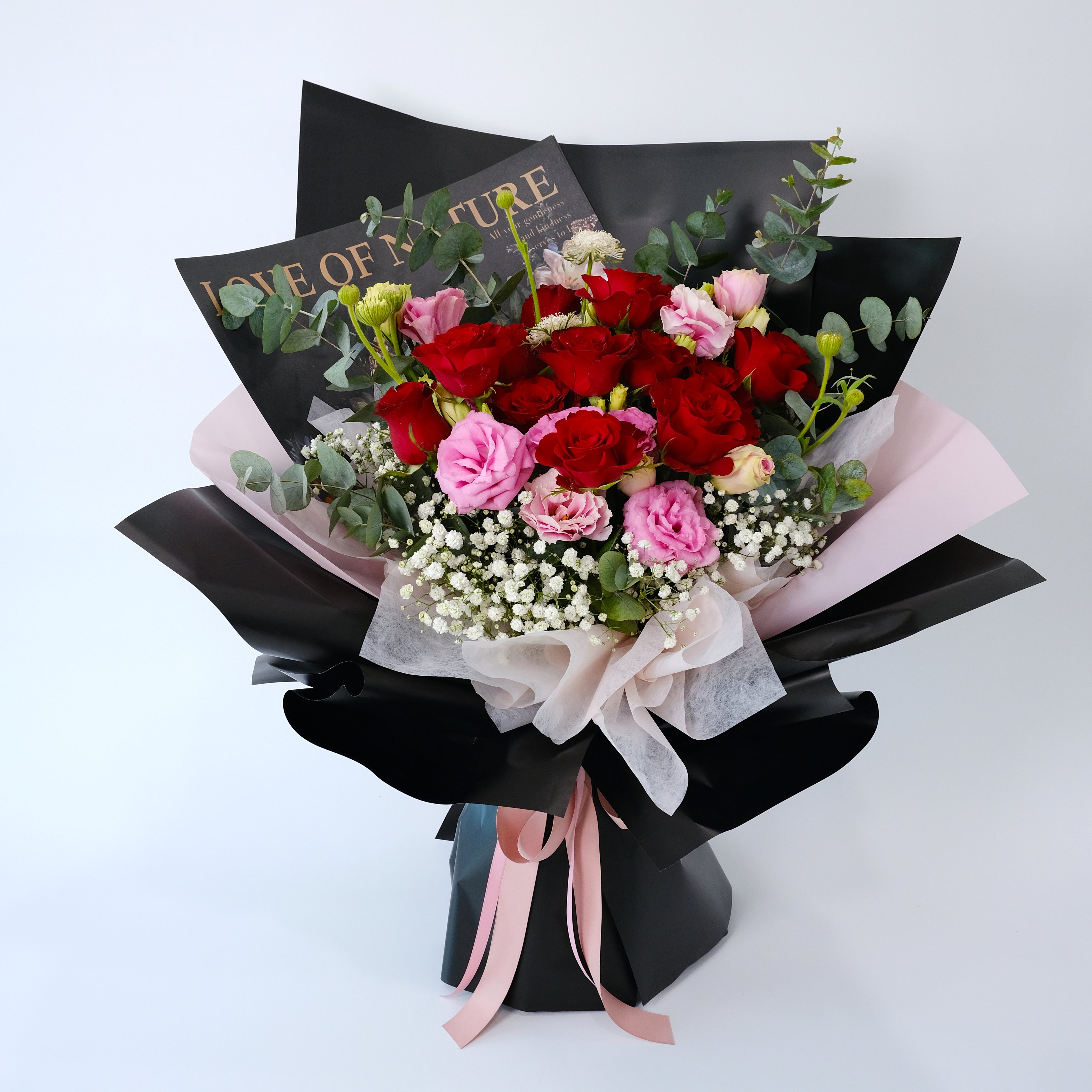 Bouquet of red and pink flowers with a black wrap and pink ribbon on a white background