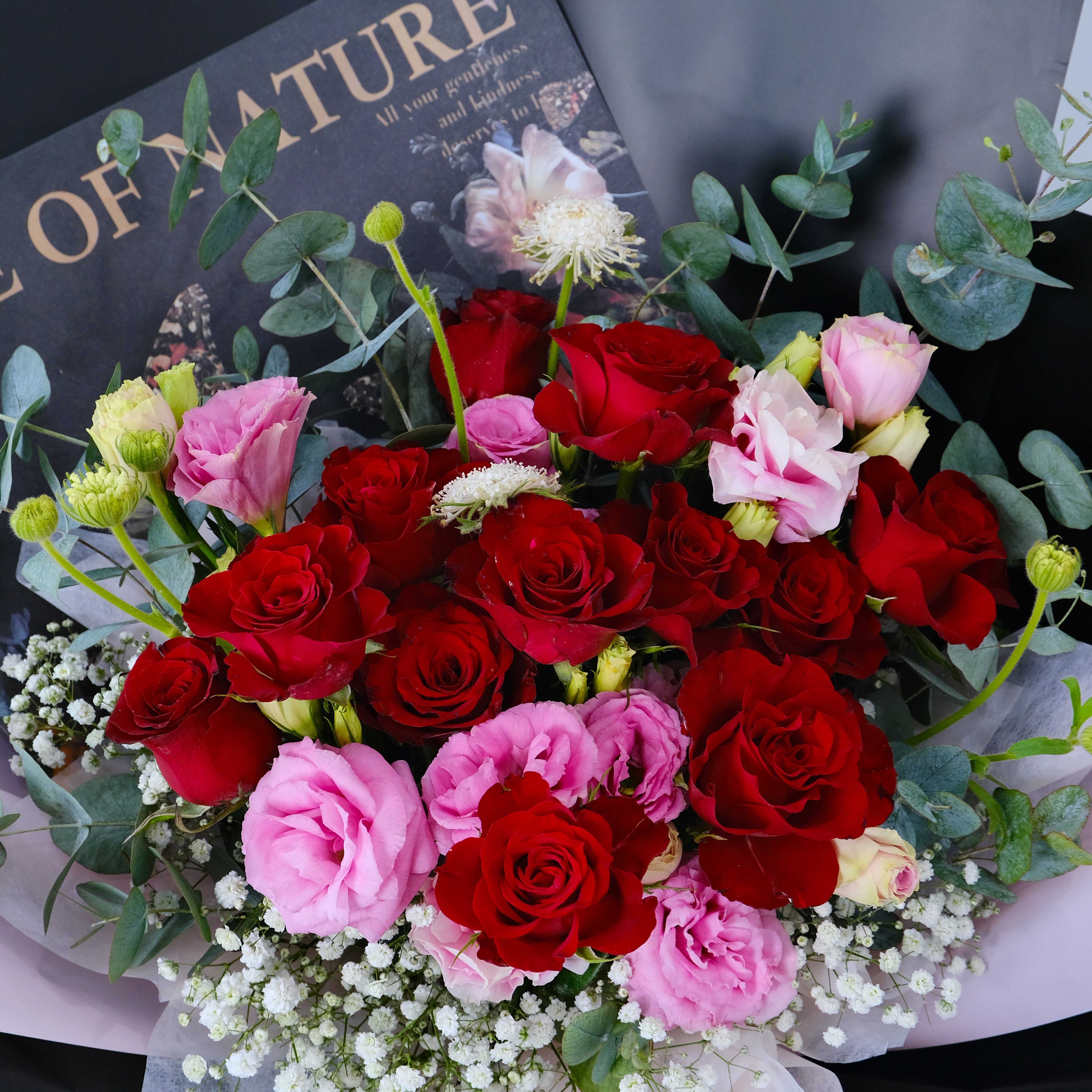 Bouquet of red and pink roses with greenery on a black background