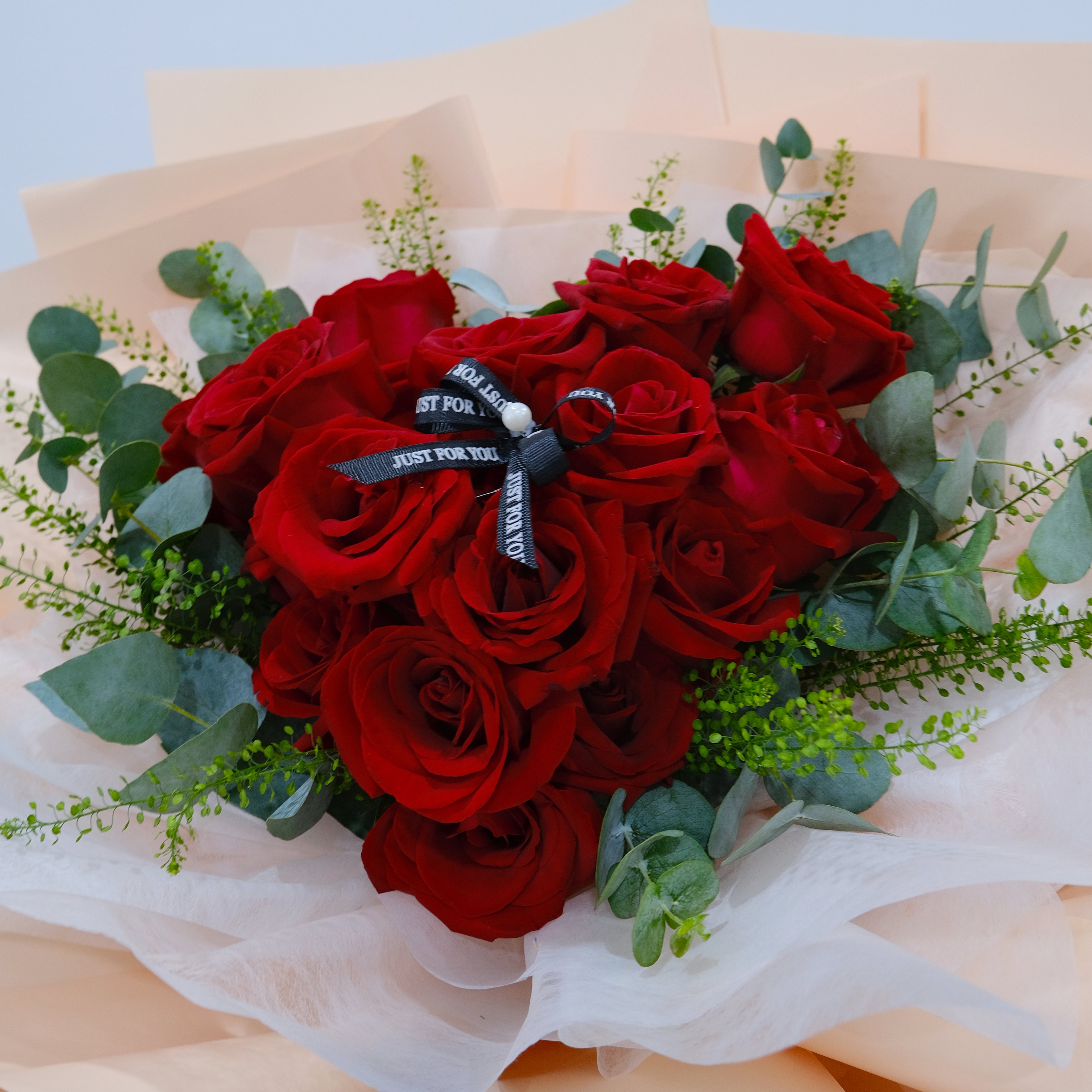 Bouquet of red roses with greenery on a light background