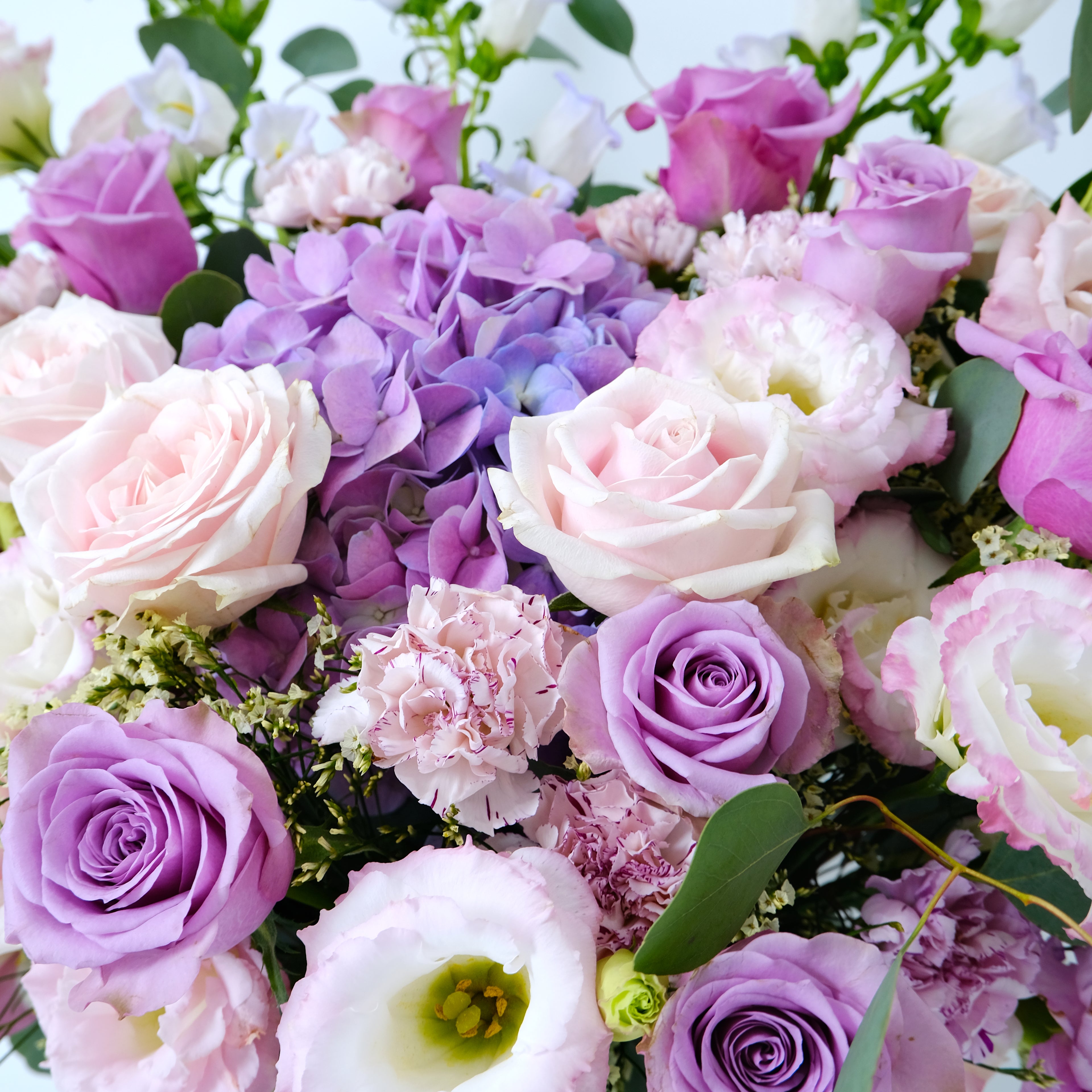 Bouquet of pink, purple, and white flowers with green leaves.