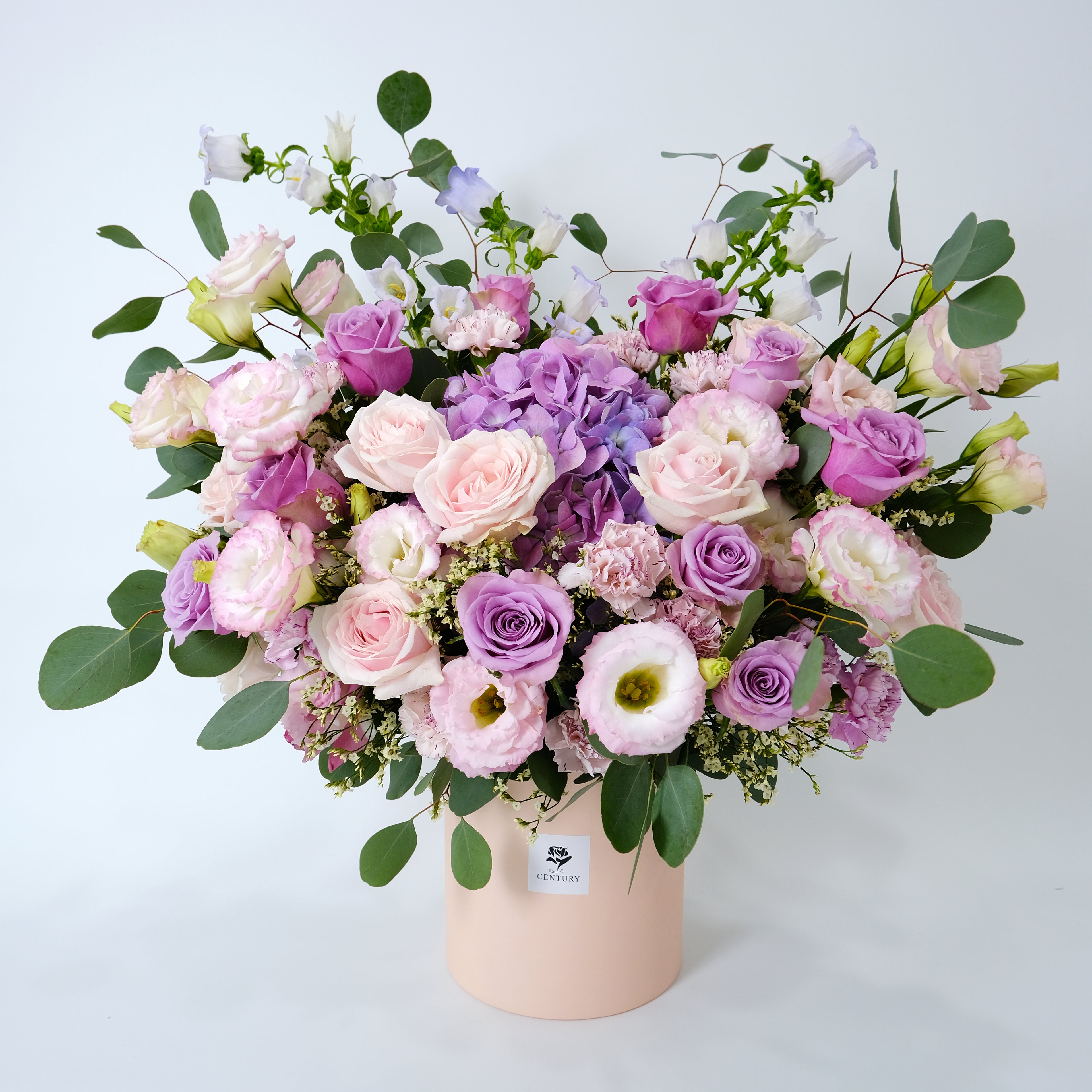 Bouquet of pink and purple flowers in a box on a light gray background