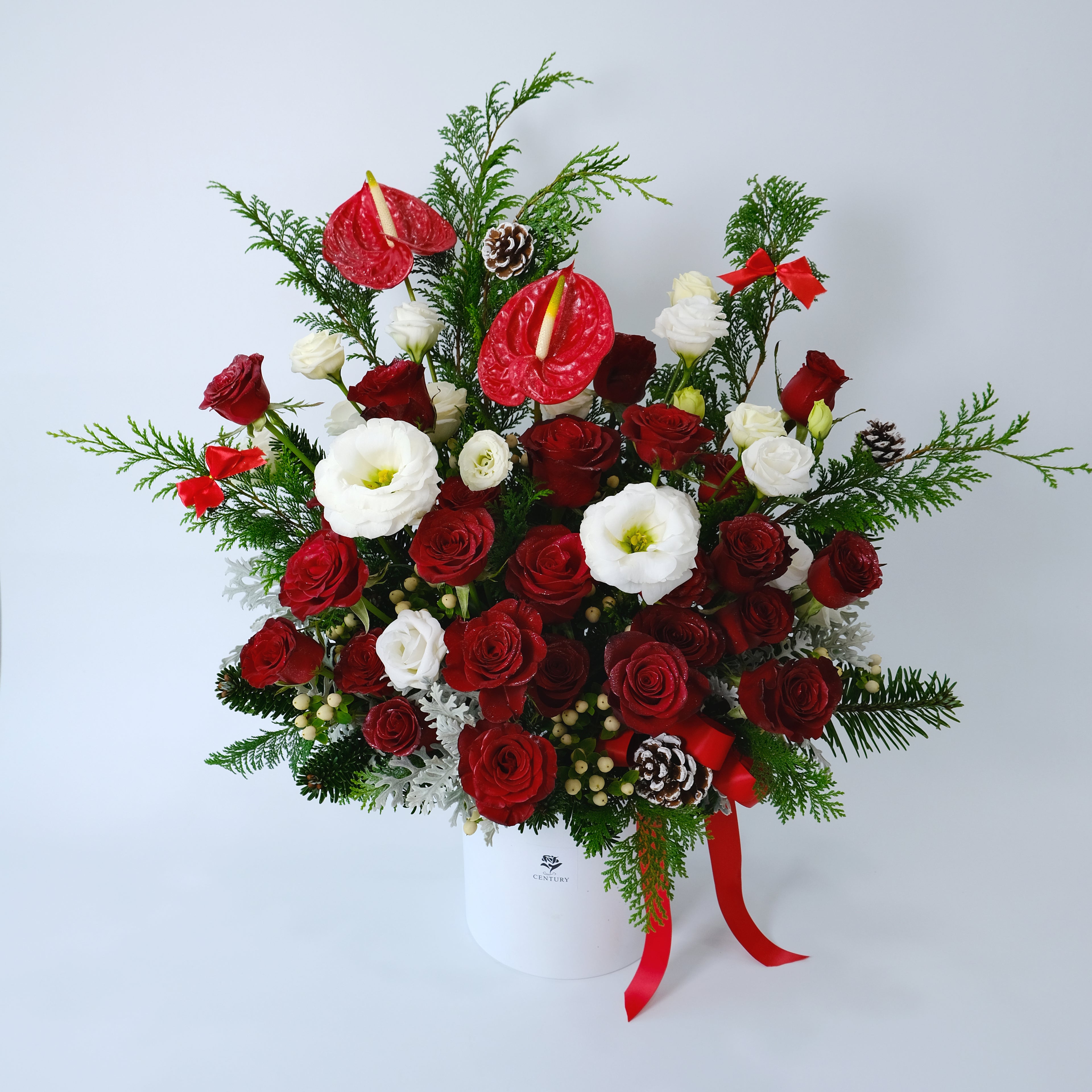 Bouquet of red and white flowers with greenery on a light gray background