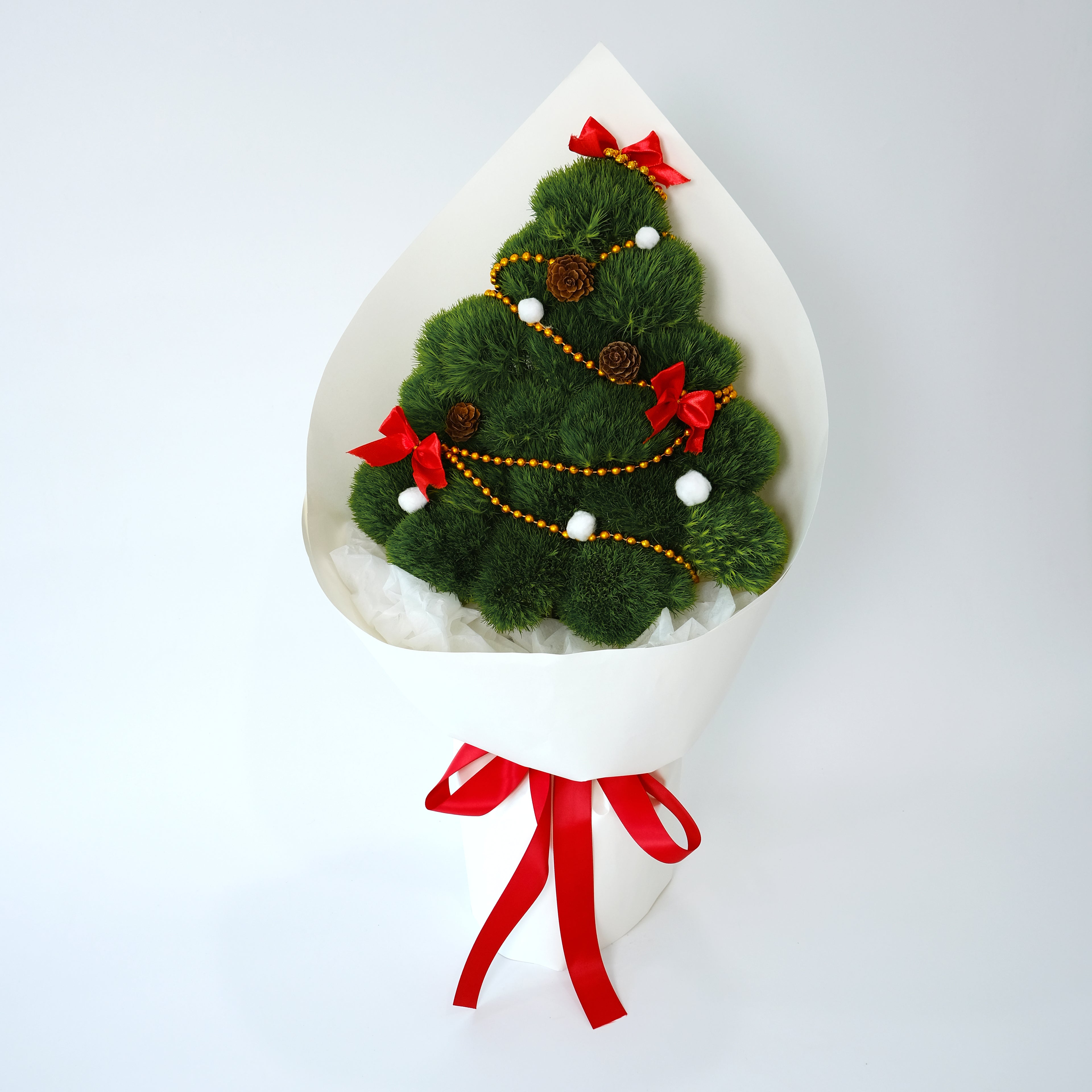 Decorative Christmas tree made of greenery with red ribbons and gold accents on a white background