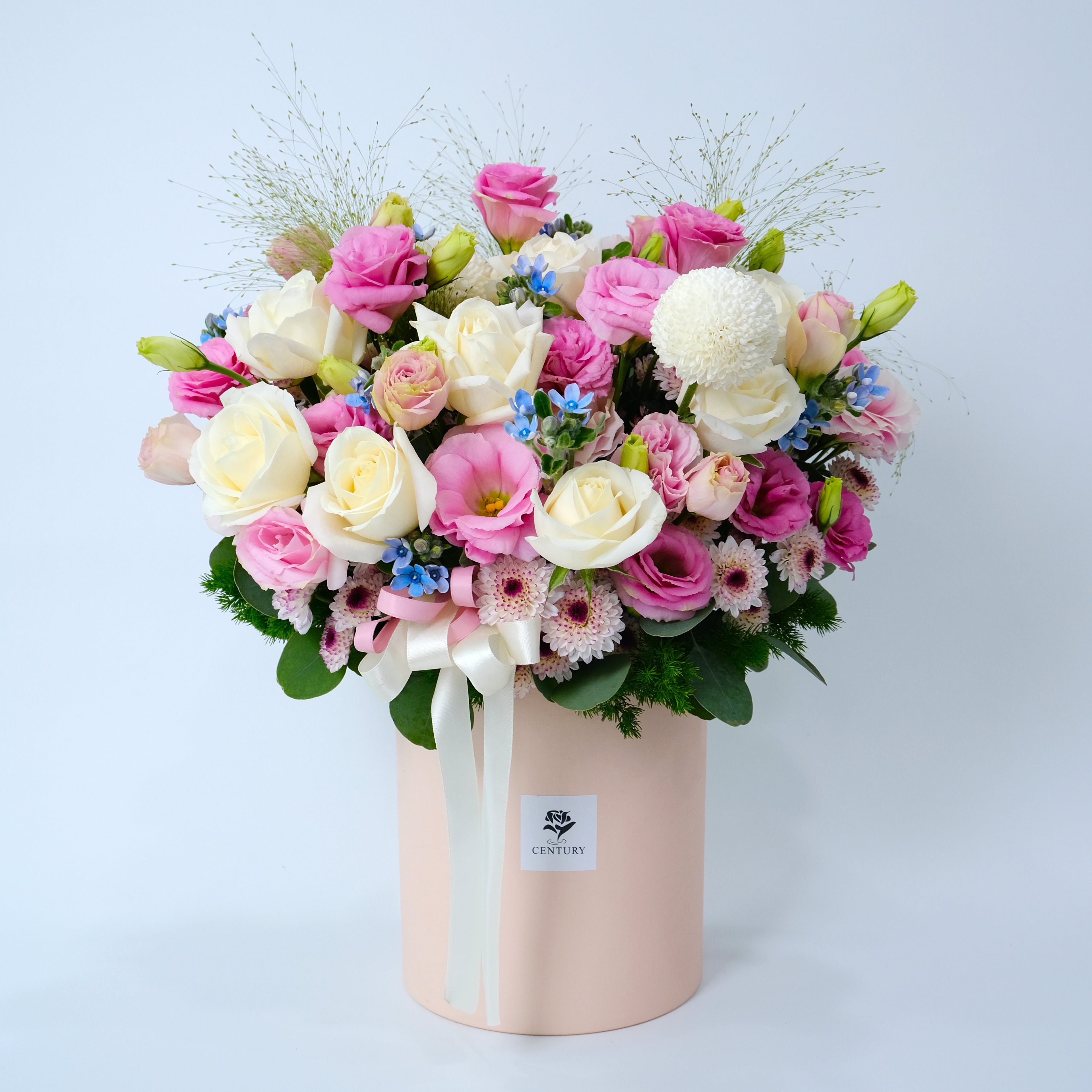 Bouquet of pink, white, and green flowers in a pink box on a light blue background