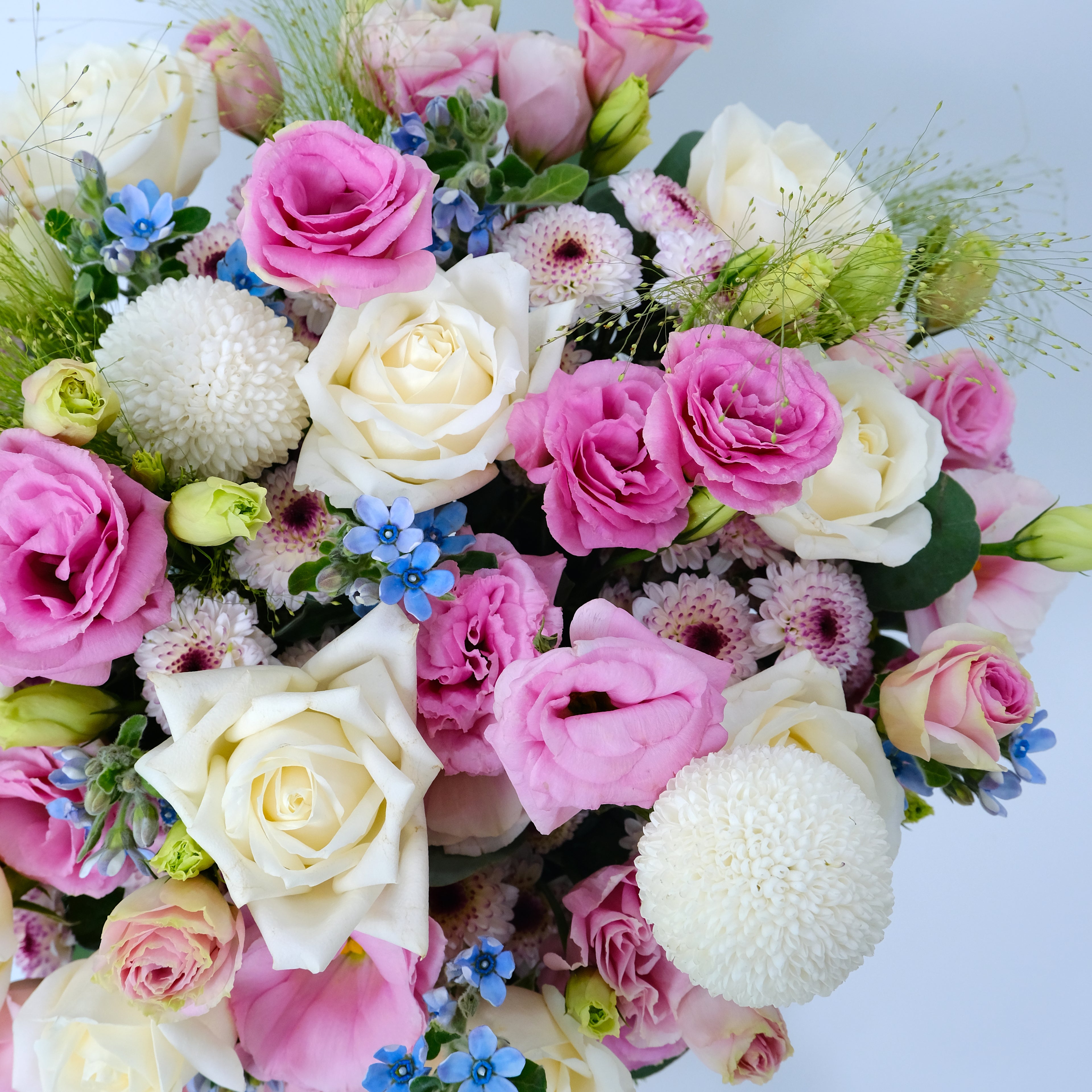 Bouquet of pink, white, and green flowers on a light blue background