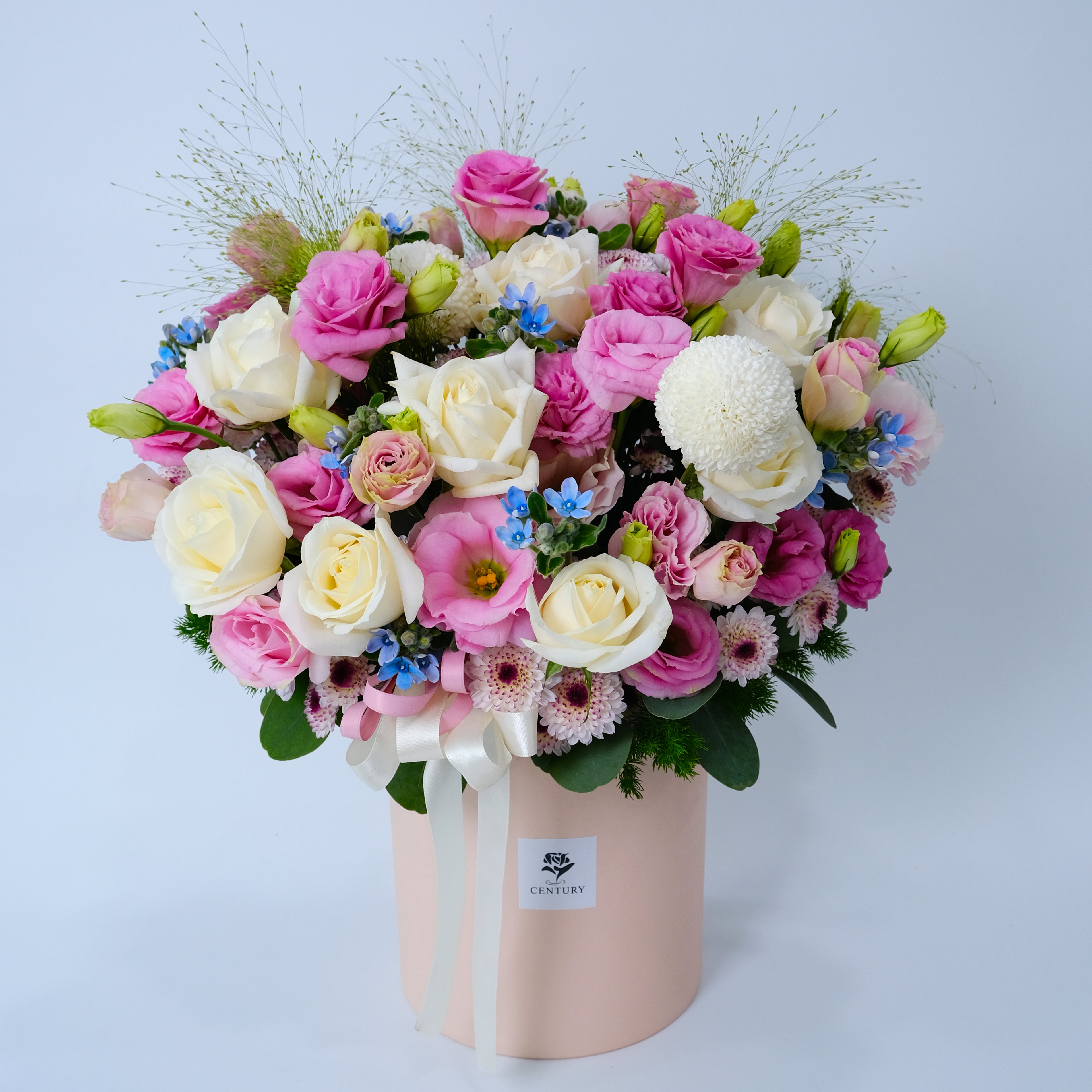 Bouquet of pink, white, and green flowers in a pink box on a light blue background