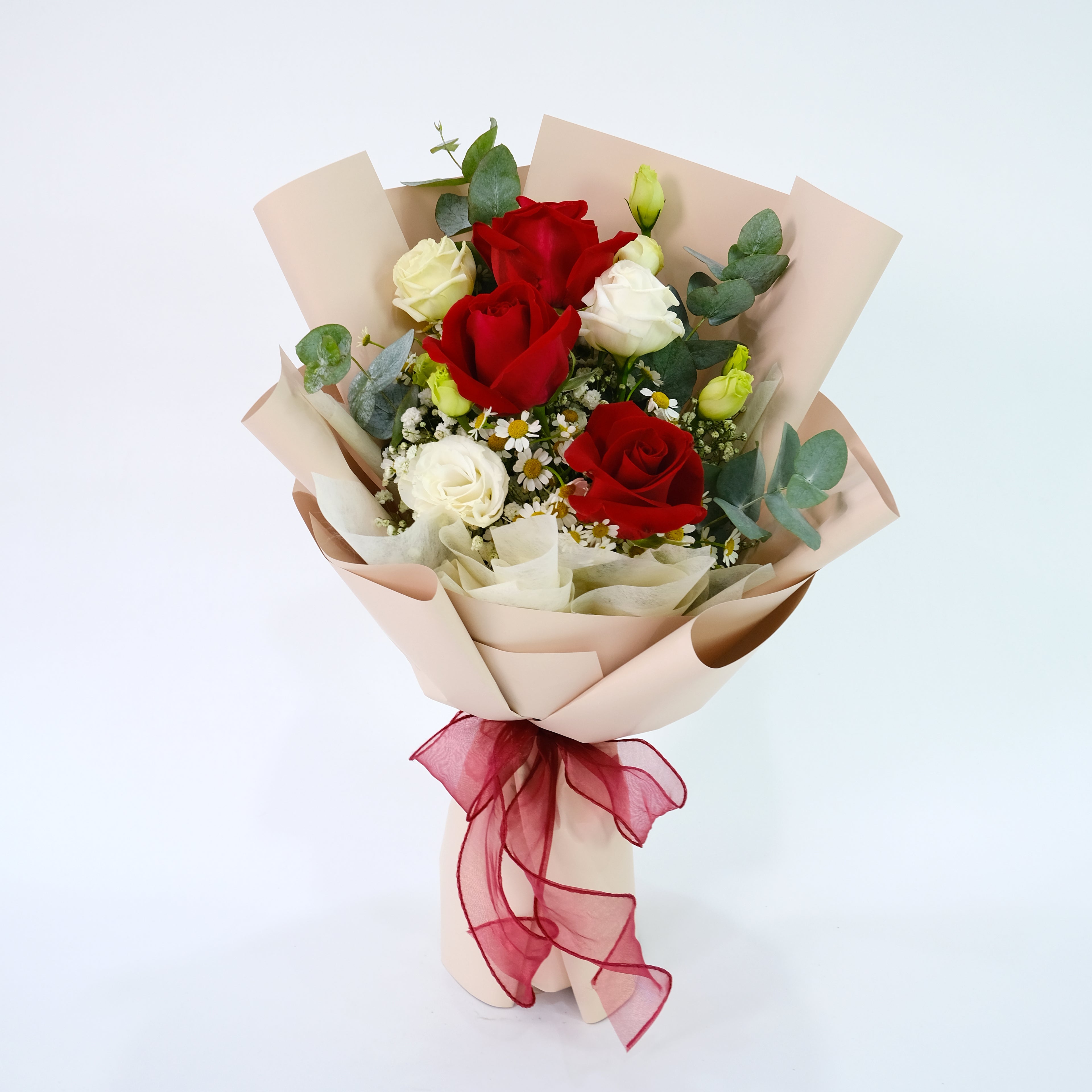 Bouquet of red and white roses with greenery wrapped in brown paper and a red ribbon on a white background