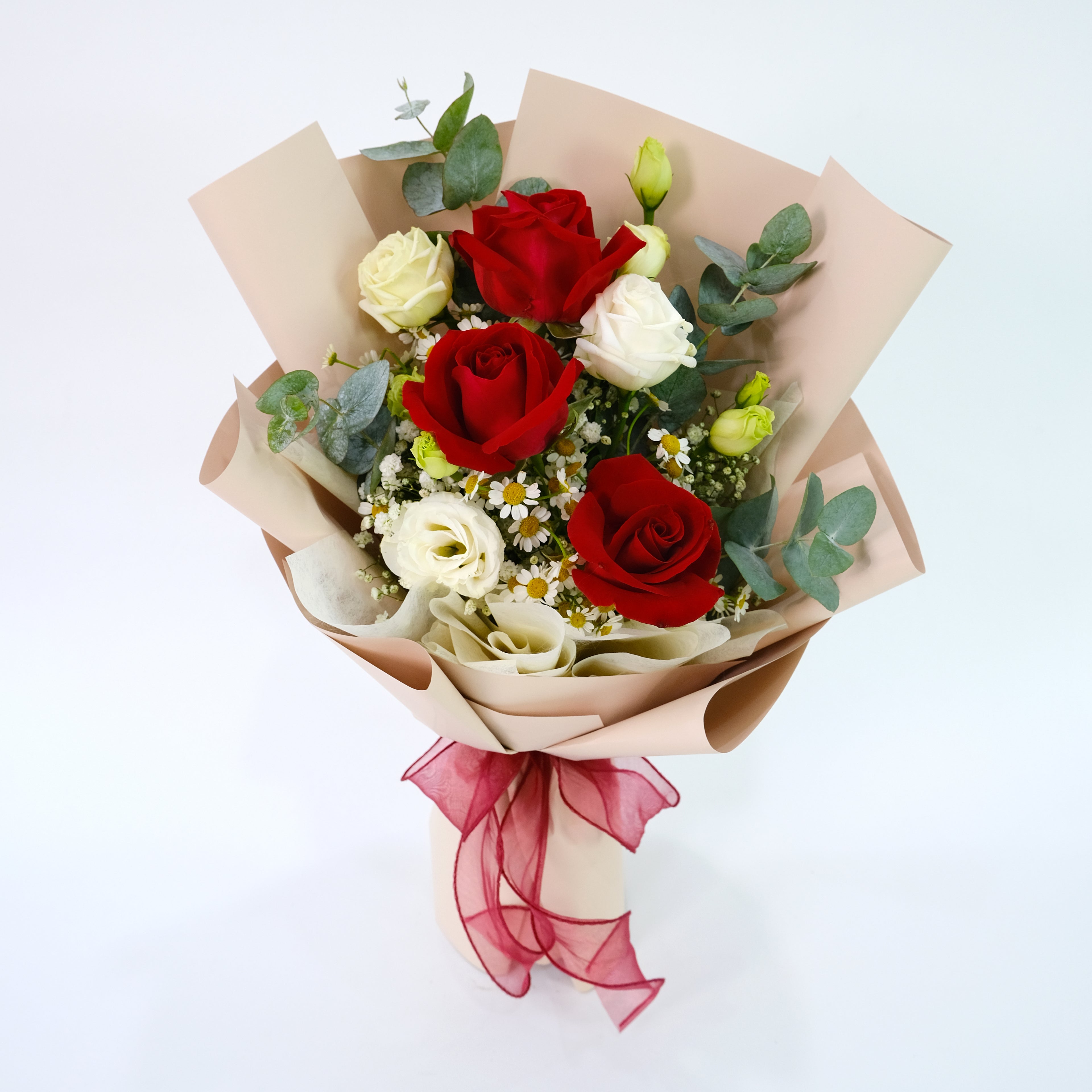 Bouquet of red and white roses with greenery on a light background