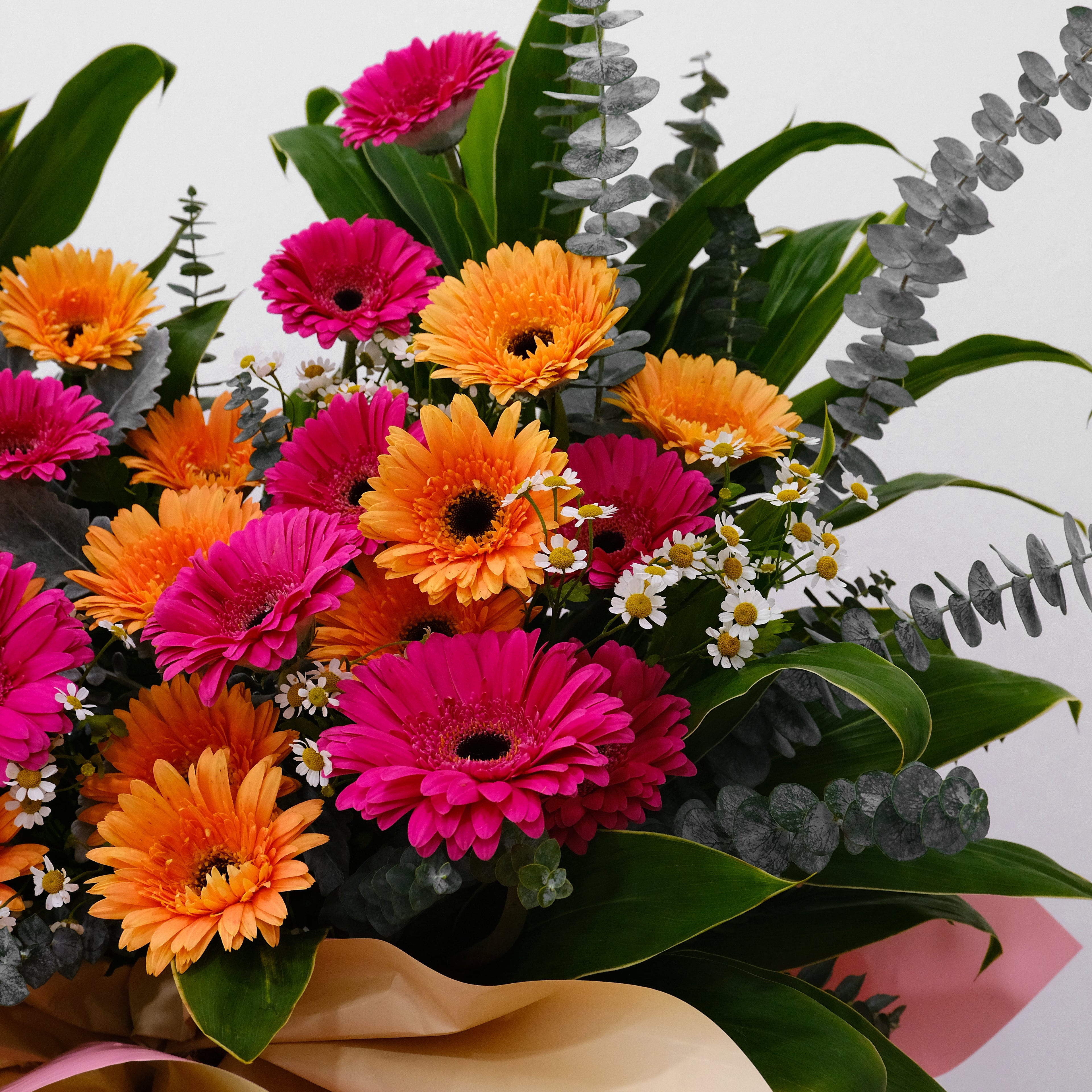 Grand opening flower stand with magenta and orange gerberas, eucalyptus, and chamomile in gold and pink wrap for luxury delivery in KL.