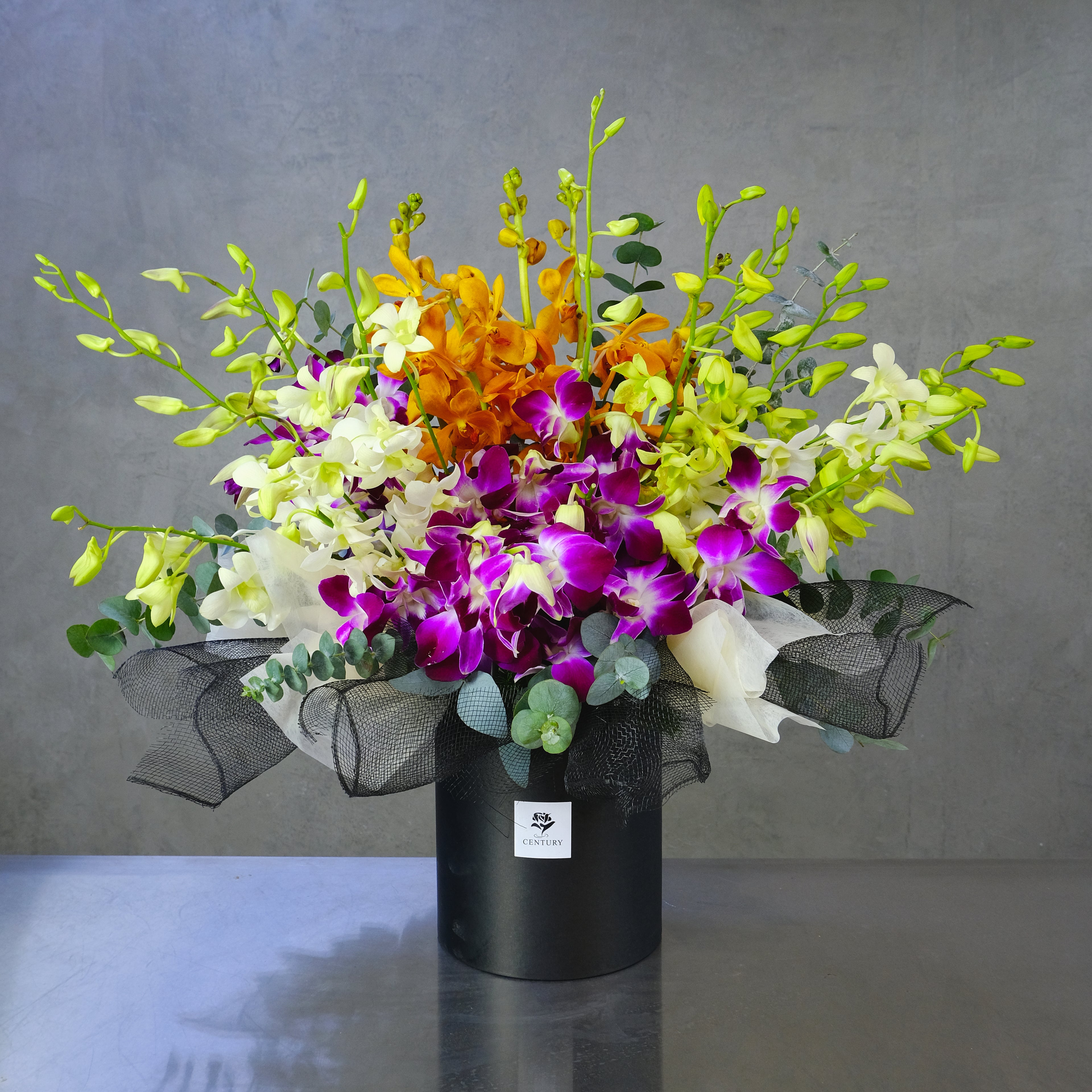 Colorful bouquet of flowers in a black container on a gray background