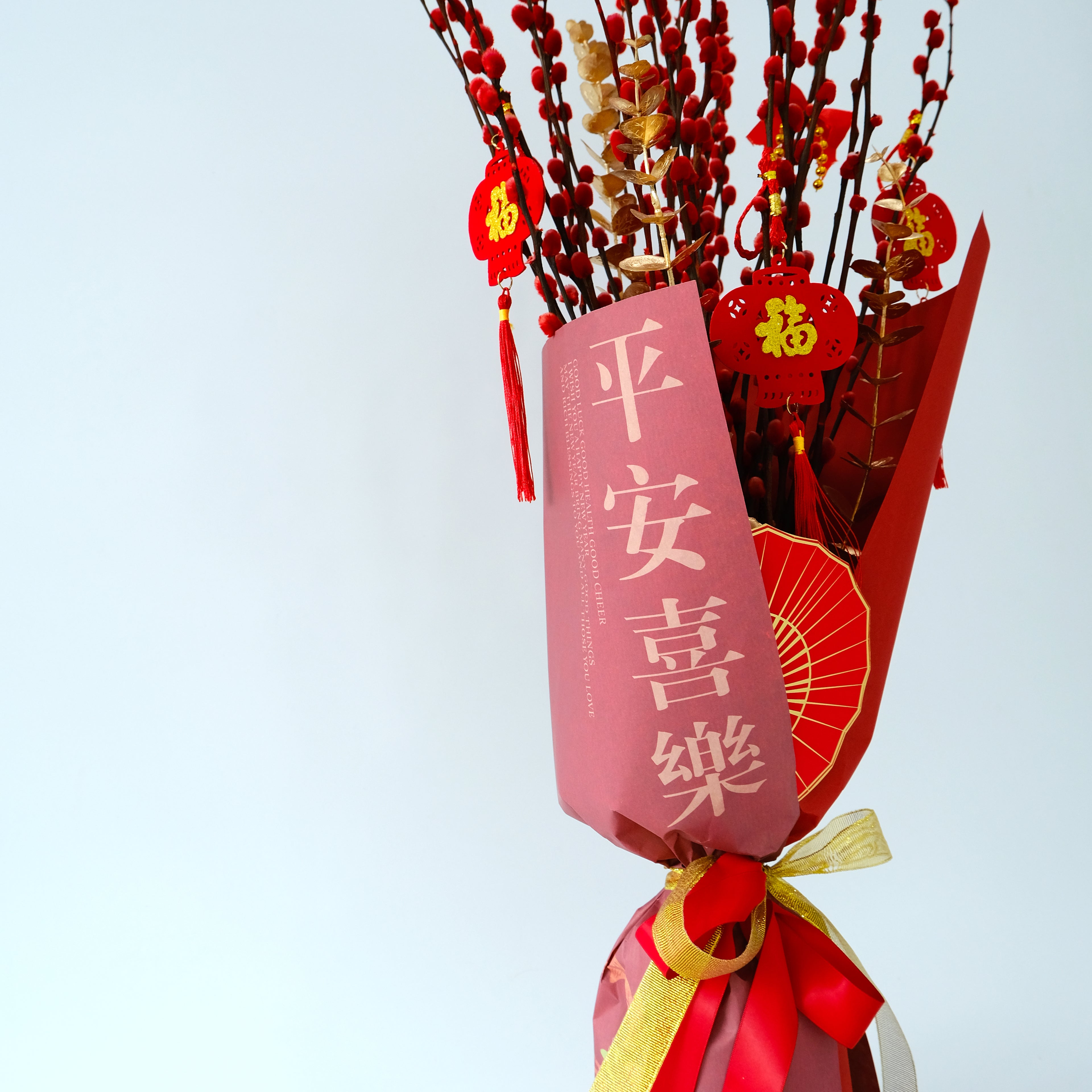 Bouquet of silver branches with red decorations and a pink card on a light blue background