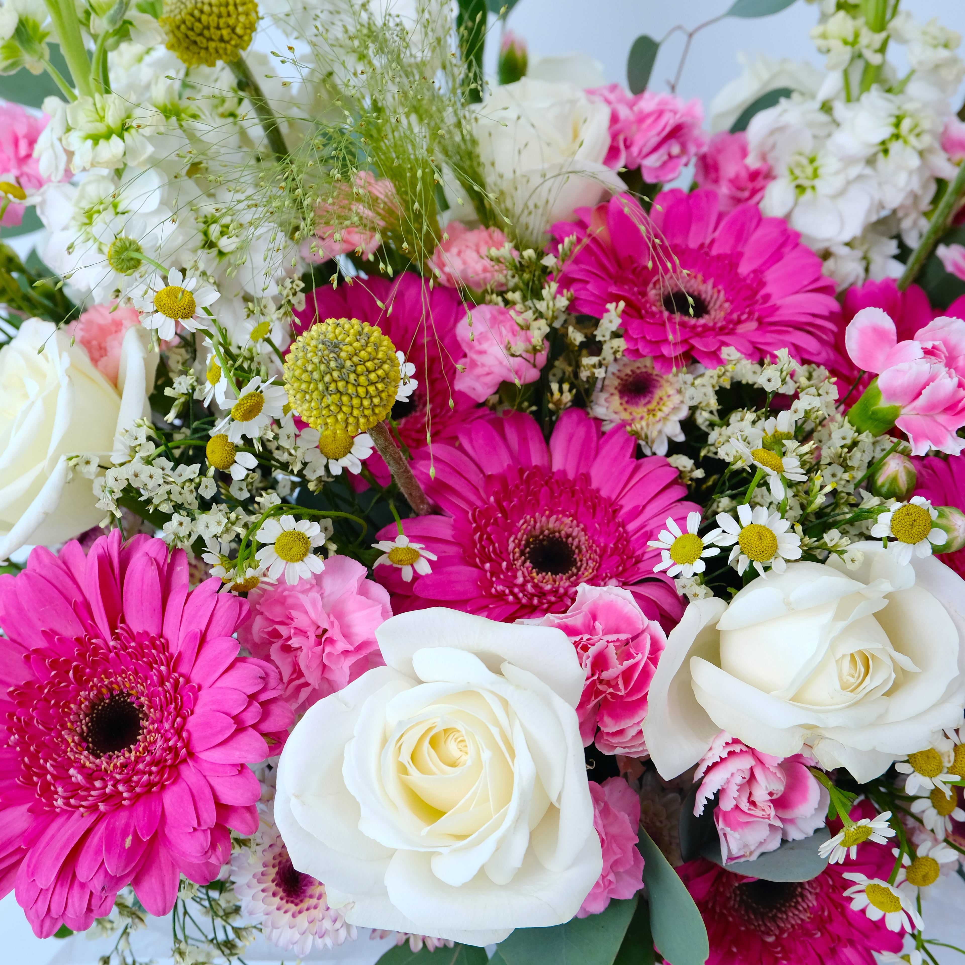 Bouquet of pink, white, and yellow flowers with green leaves.