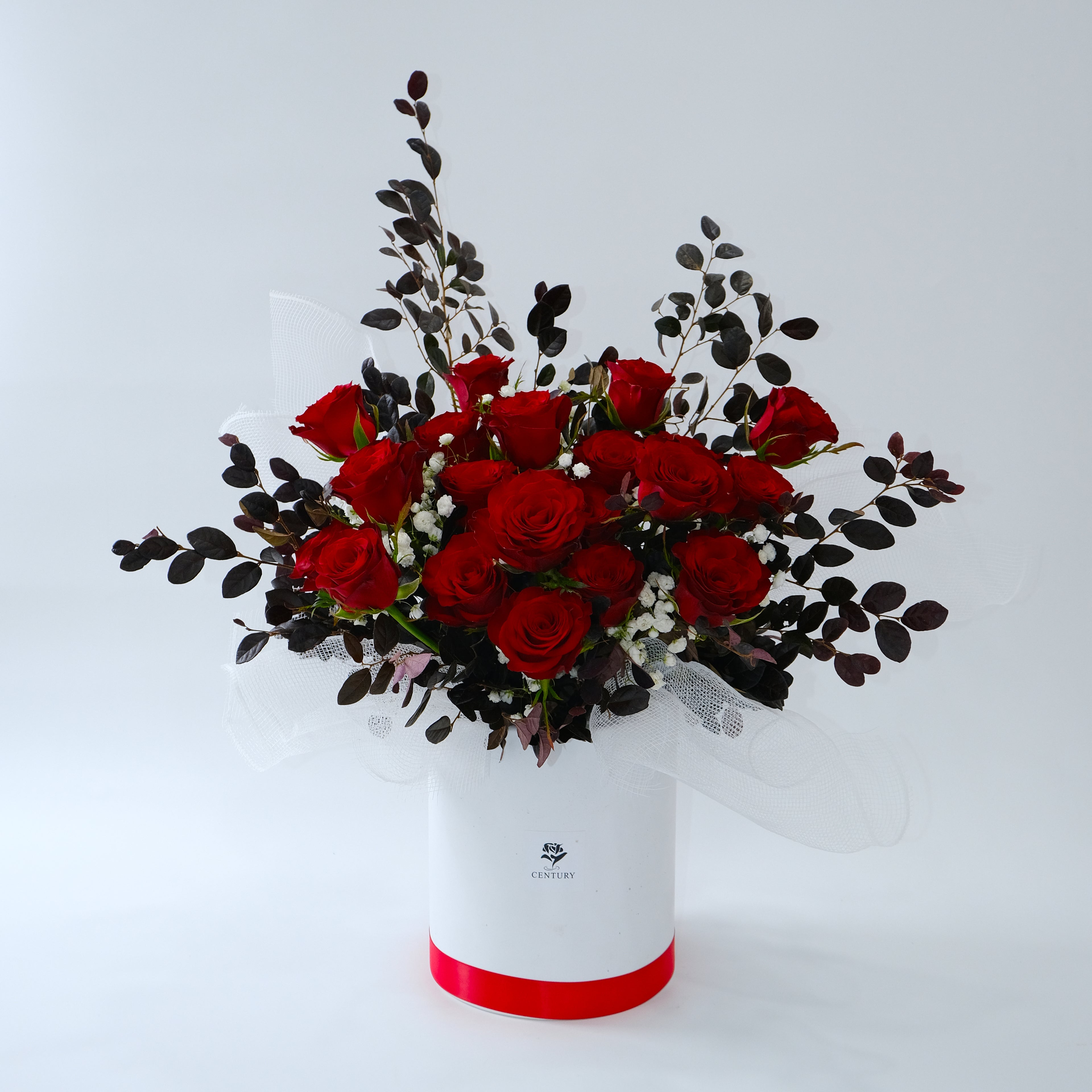 Bouquet of red roses in a white box with a red bottom on a light gray background
