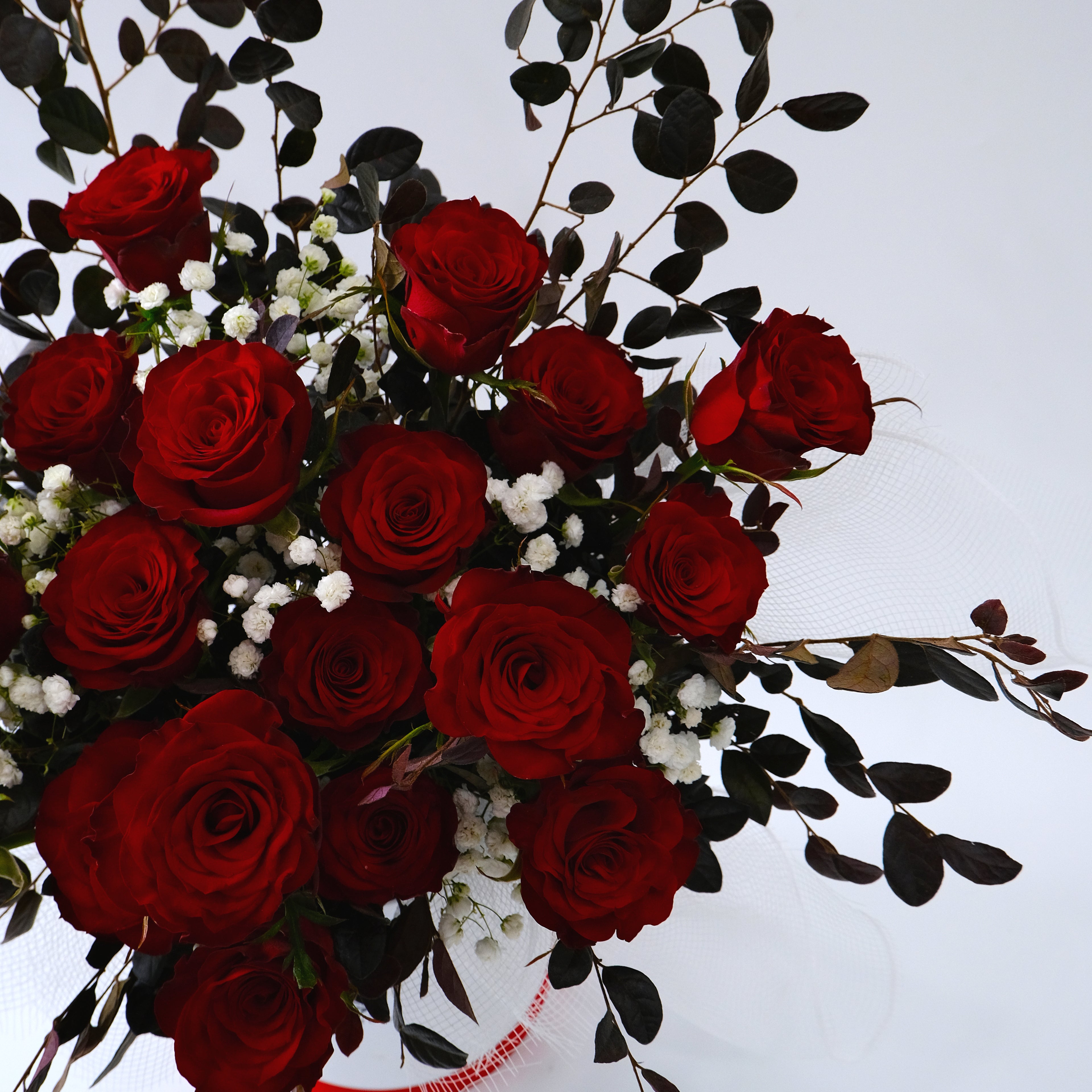 Bouquet of red roses with greenery on a white background